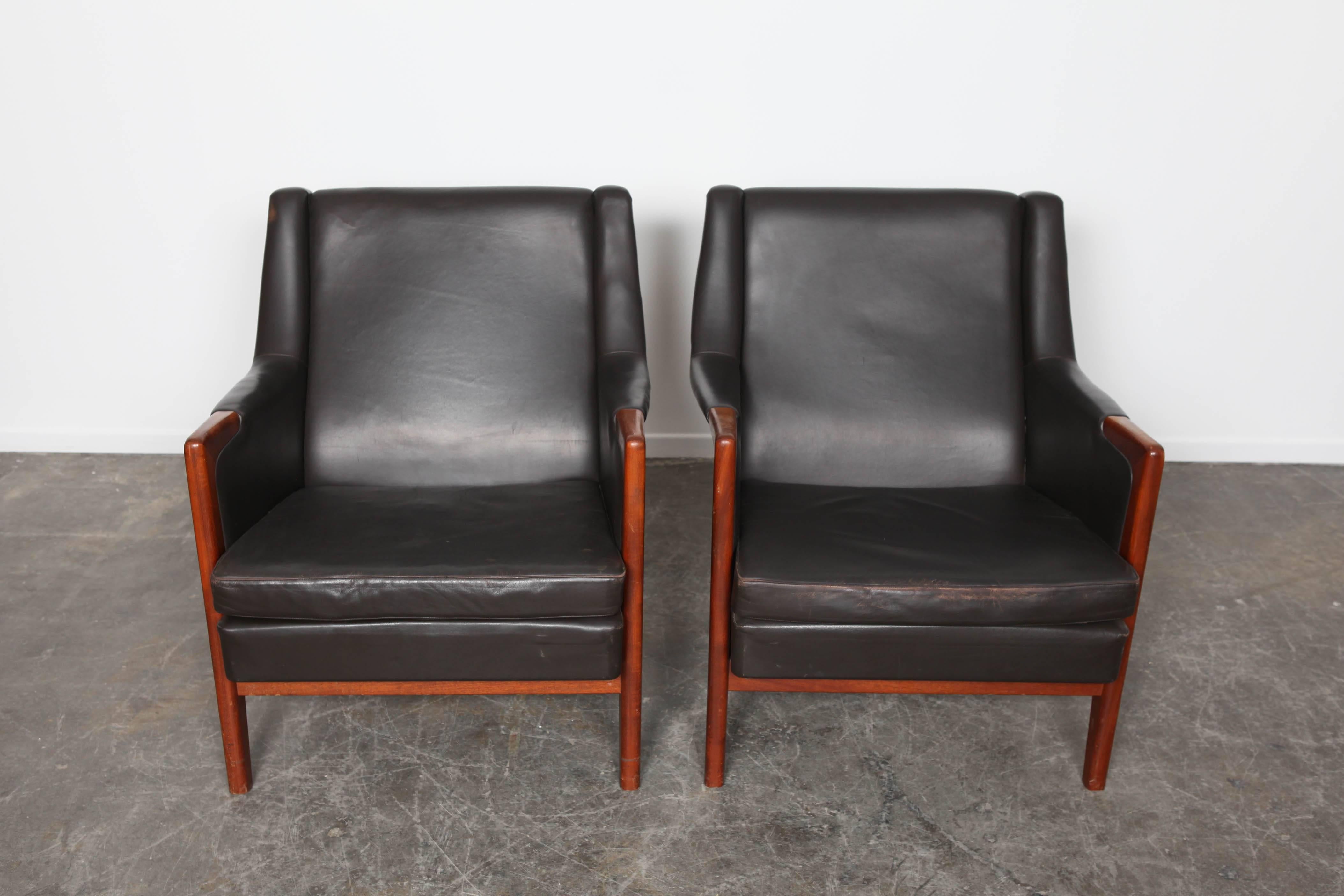 Pair of black leather lounge chairs Karl Erik Ekselius with front wooden legs that transition up to armrest.