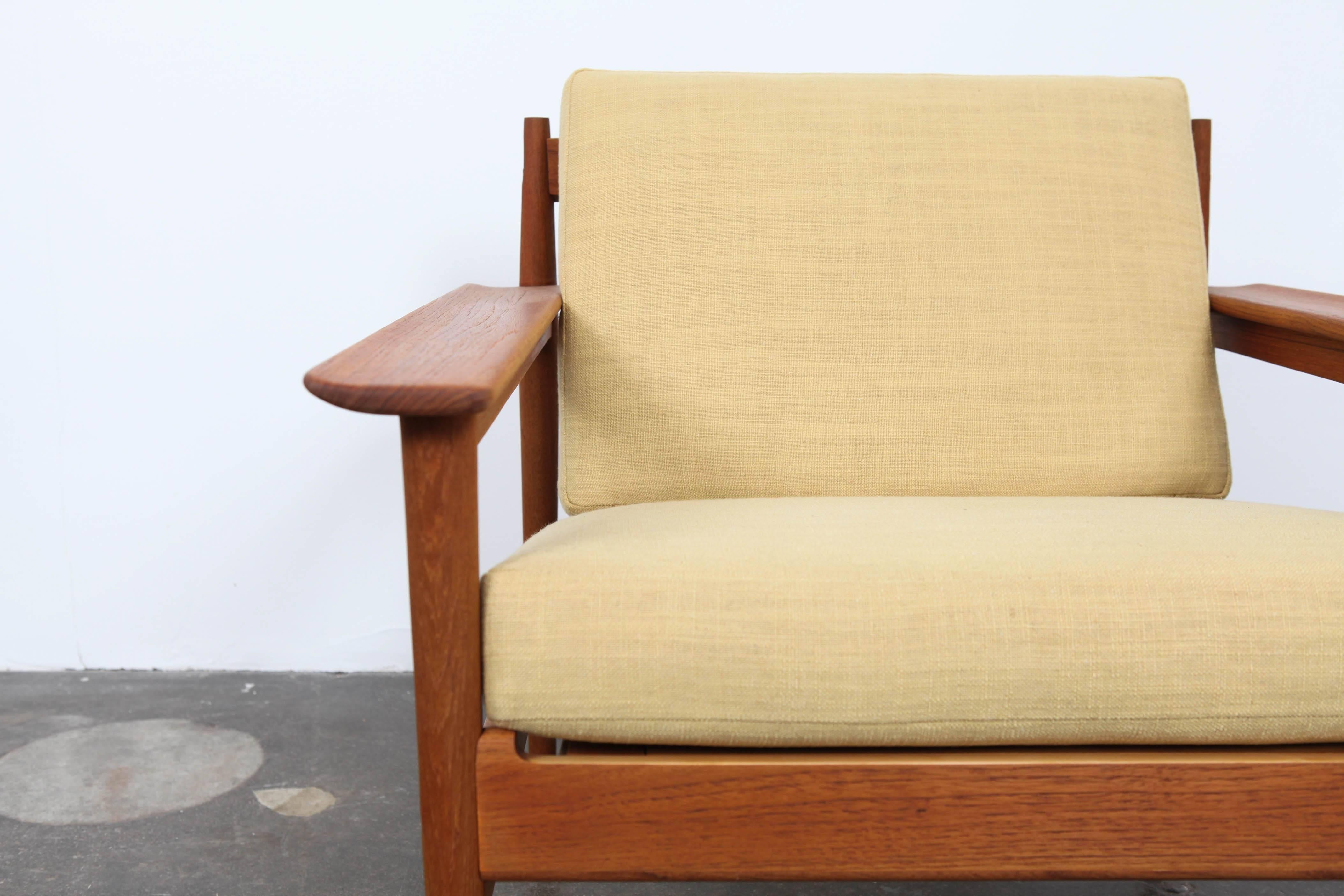 Pair of Swedish open-frame teak lounge chairs with slatted backs, round tapered legs and loose cushions. These chairs have been newly refinished and reupholstered in a soft yellow linen fabric.