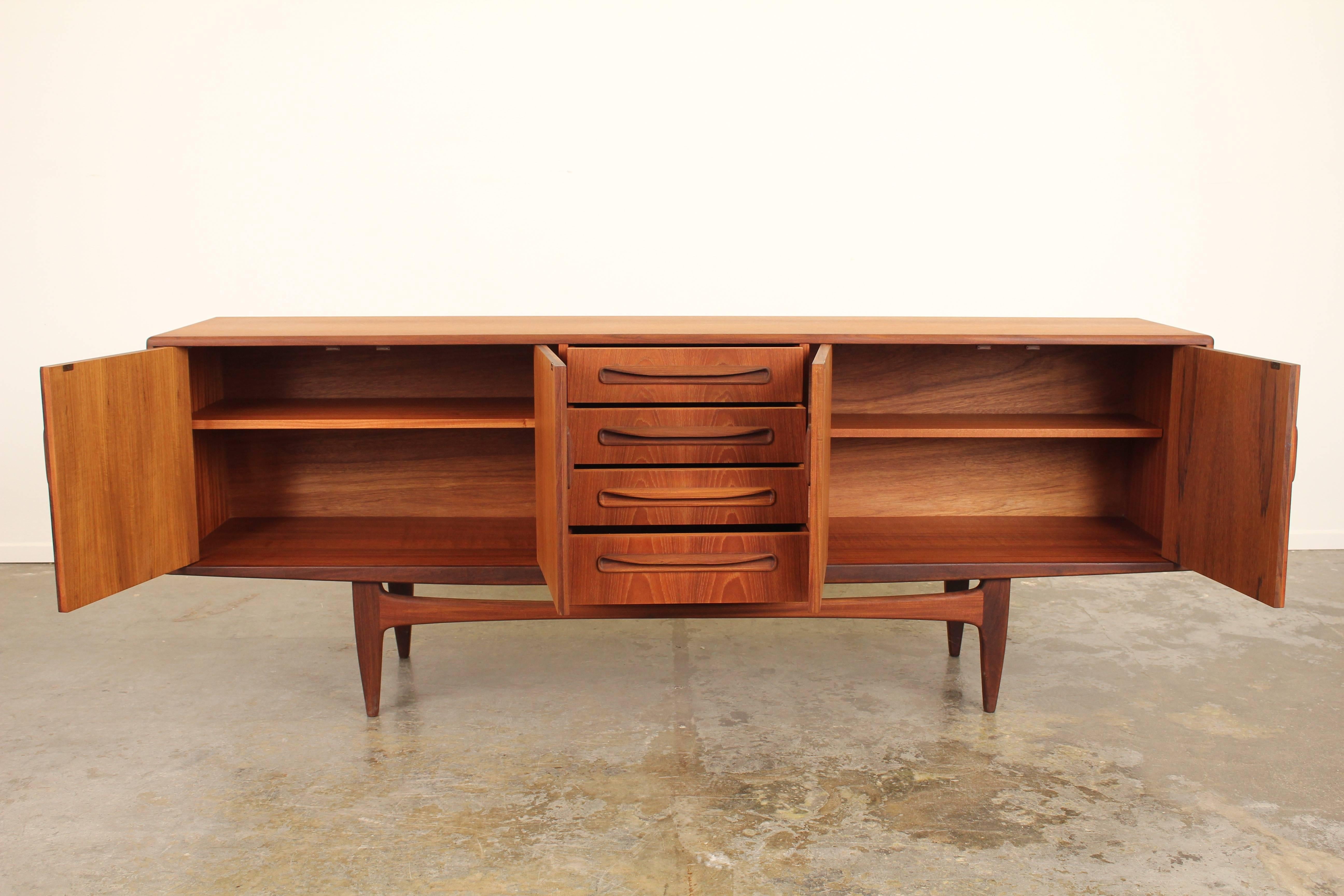 Fantastic teak sideboard made in England by G-Plan.  Beautiful butterfly and catherdral grain throughout the piece.  Carved handles and sculptural legs made out of a contrasting teak.  Newly refinished.