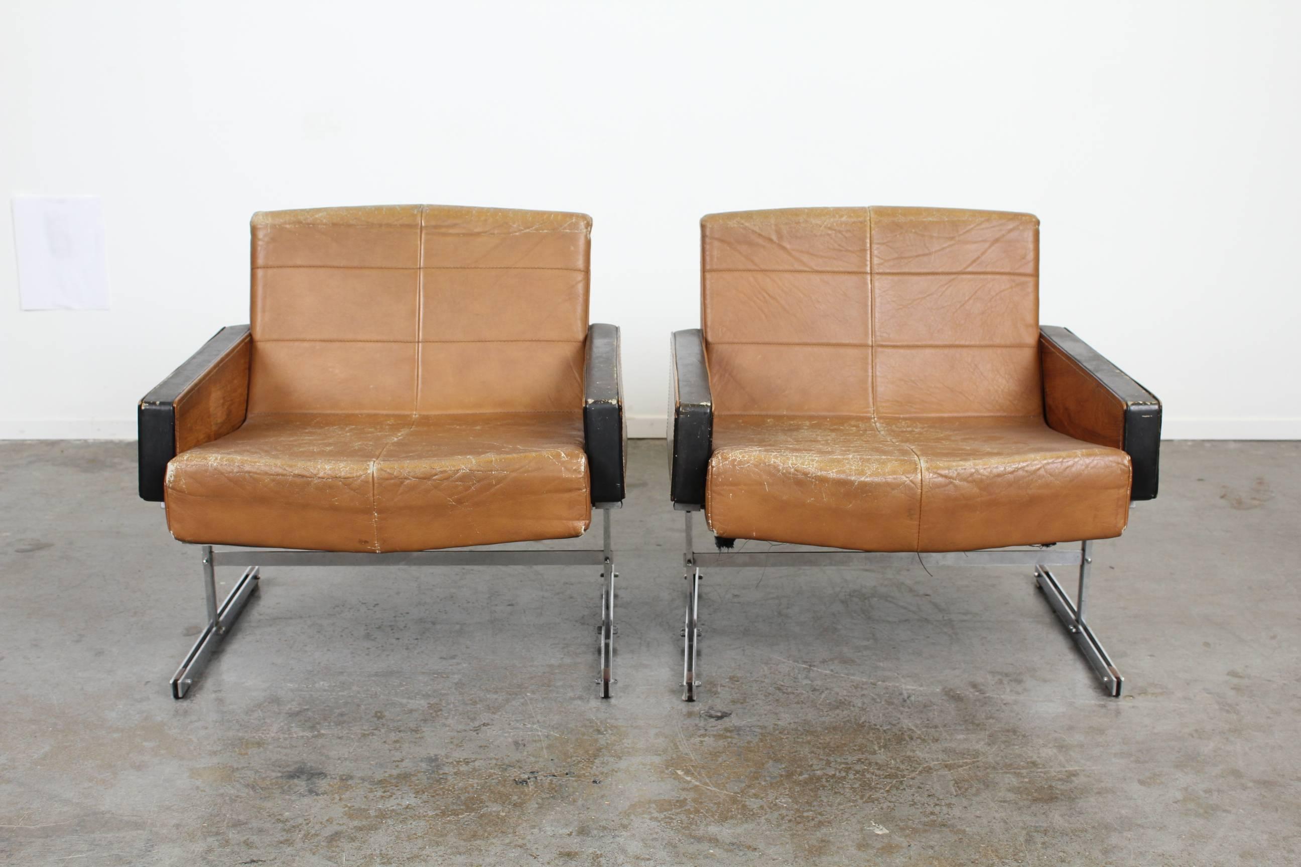 Very rare leather and rosewood chairs on metal legs with stitched tufting. Contrasting darker leather arms with rosewood side inserts define these beautiful chairs. Matching sofa and coffee table if wanted.