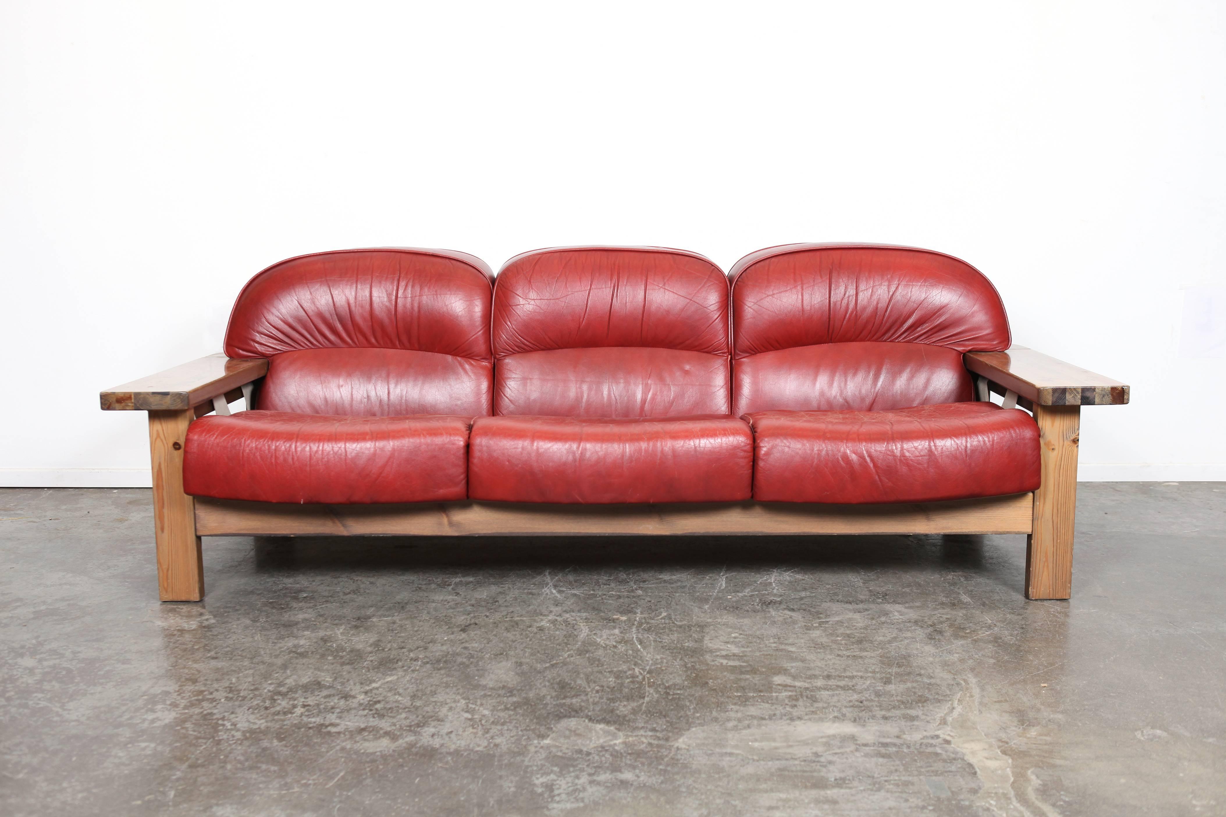 Mid-Century Modern very unique solid pine three-seat sofa with original red curved leather cushions, designed by Hämeen Kalustaja, Finland, 1970's. Matching two-seat sofa available for purchase separately.