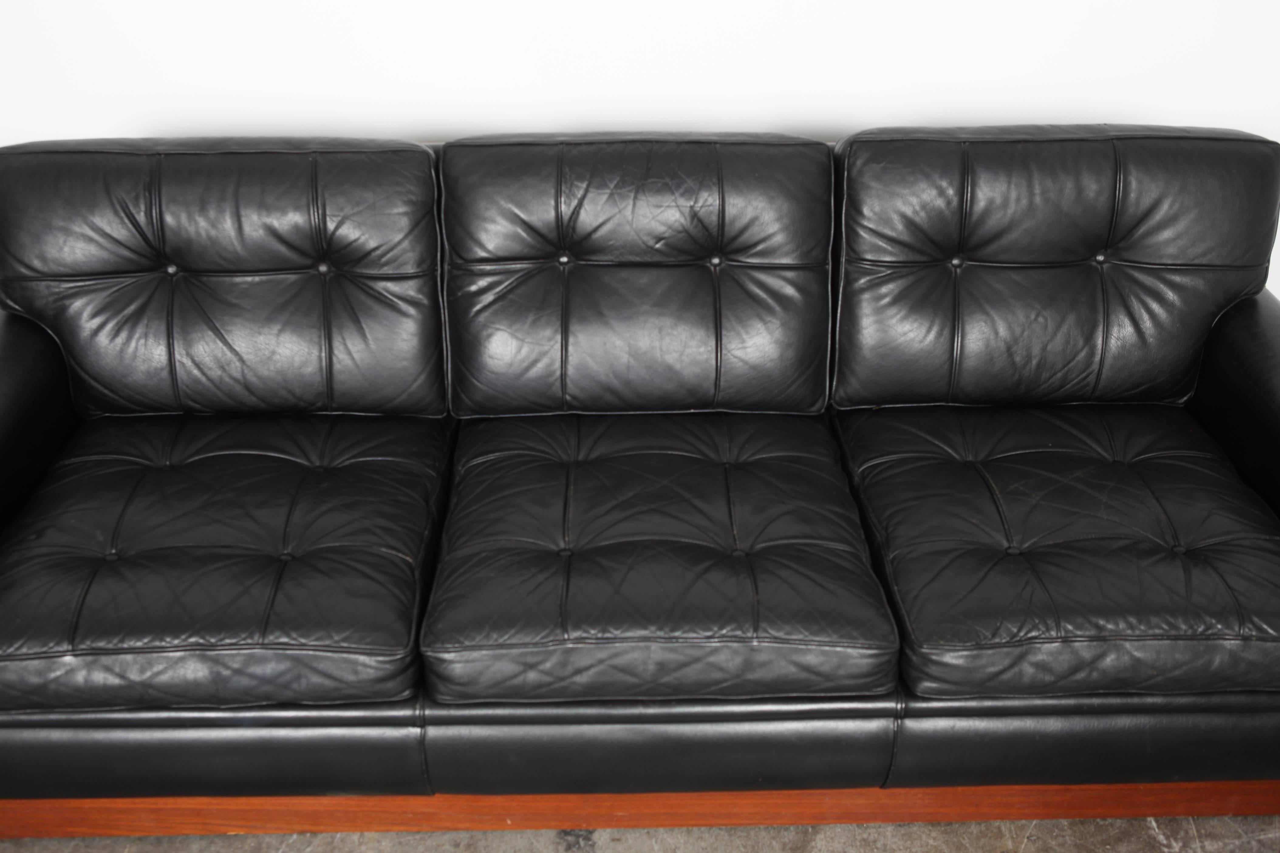 Swedish Mid-Century Modern black leather sofa on teak plinth base by Arne Norell.
