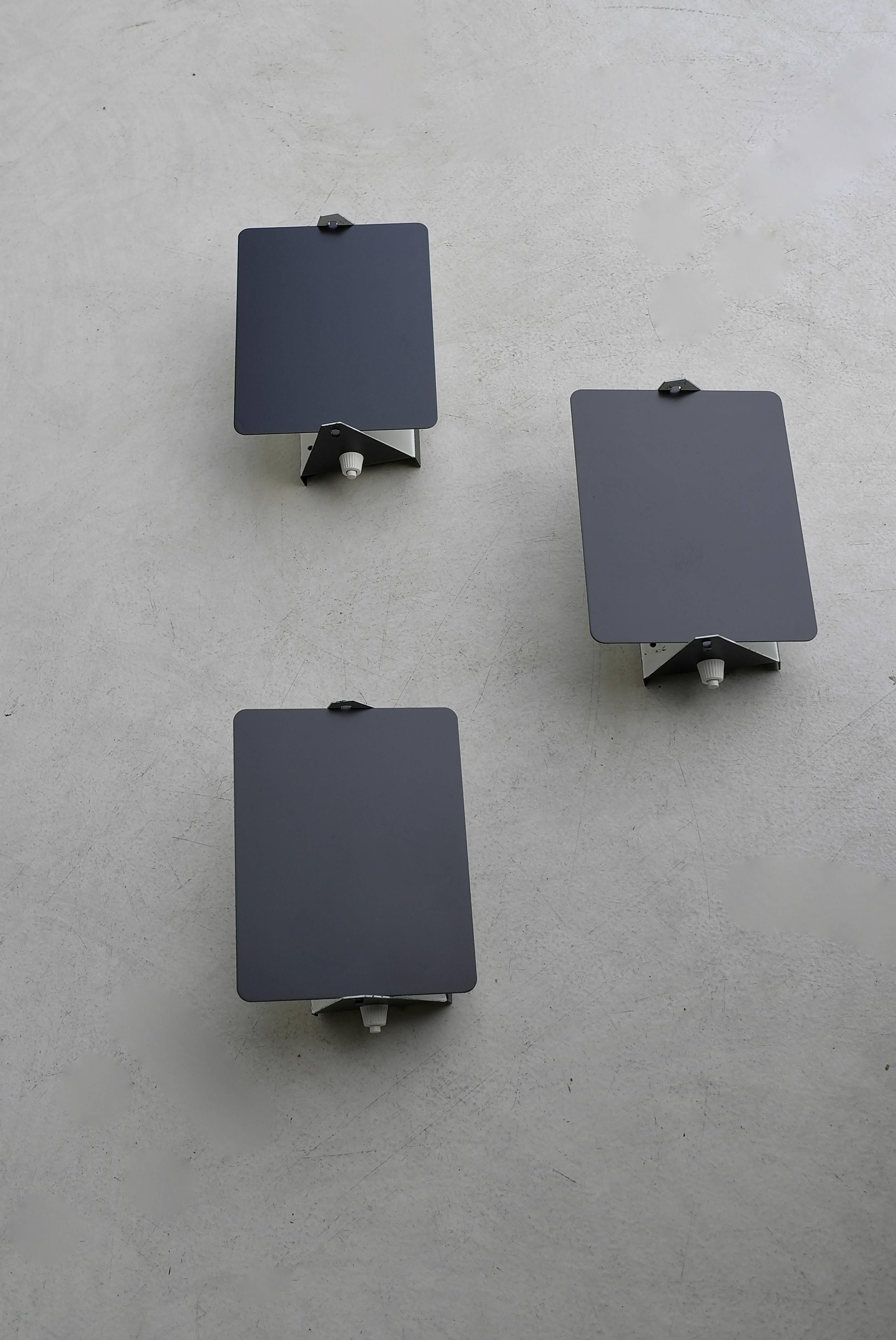 Black and white enameled pivoting wall lights by Charlotte Perriand for Les Arcs Ski Resort. Lamps can be arranged in many configurations to accommodate all living environments.