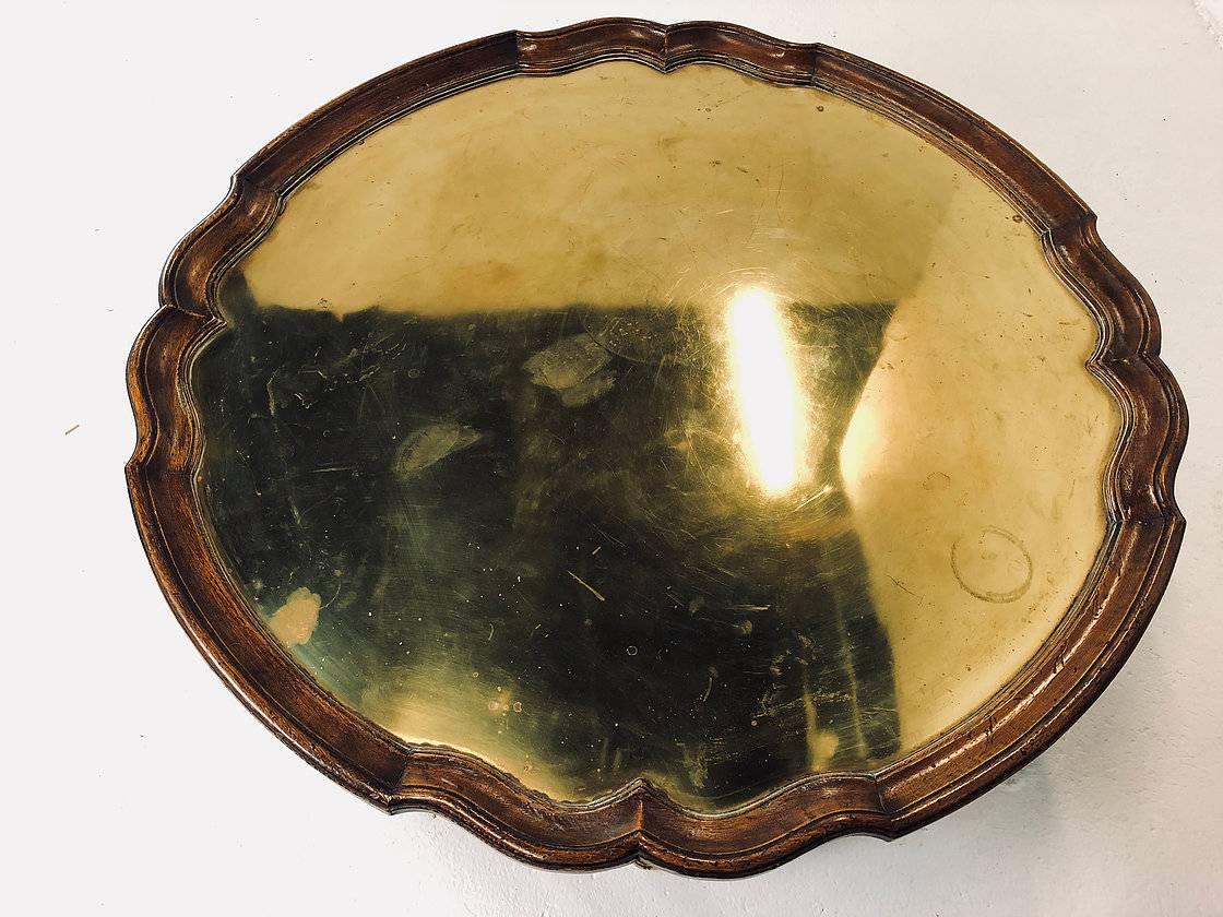 Wood and brass accented pie crust coffee table with gold mirrored glass. Coffee table shows wear and tear from use and age. There are discoloration and marks in the gold mirror finish and needs replacing. circa 1960s

dimensions:
42