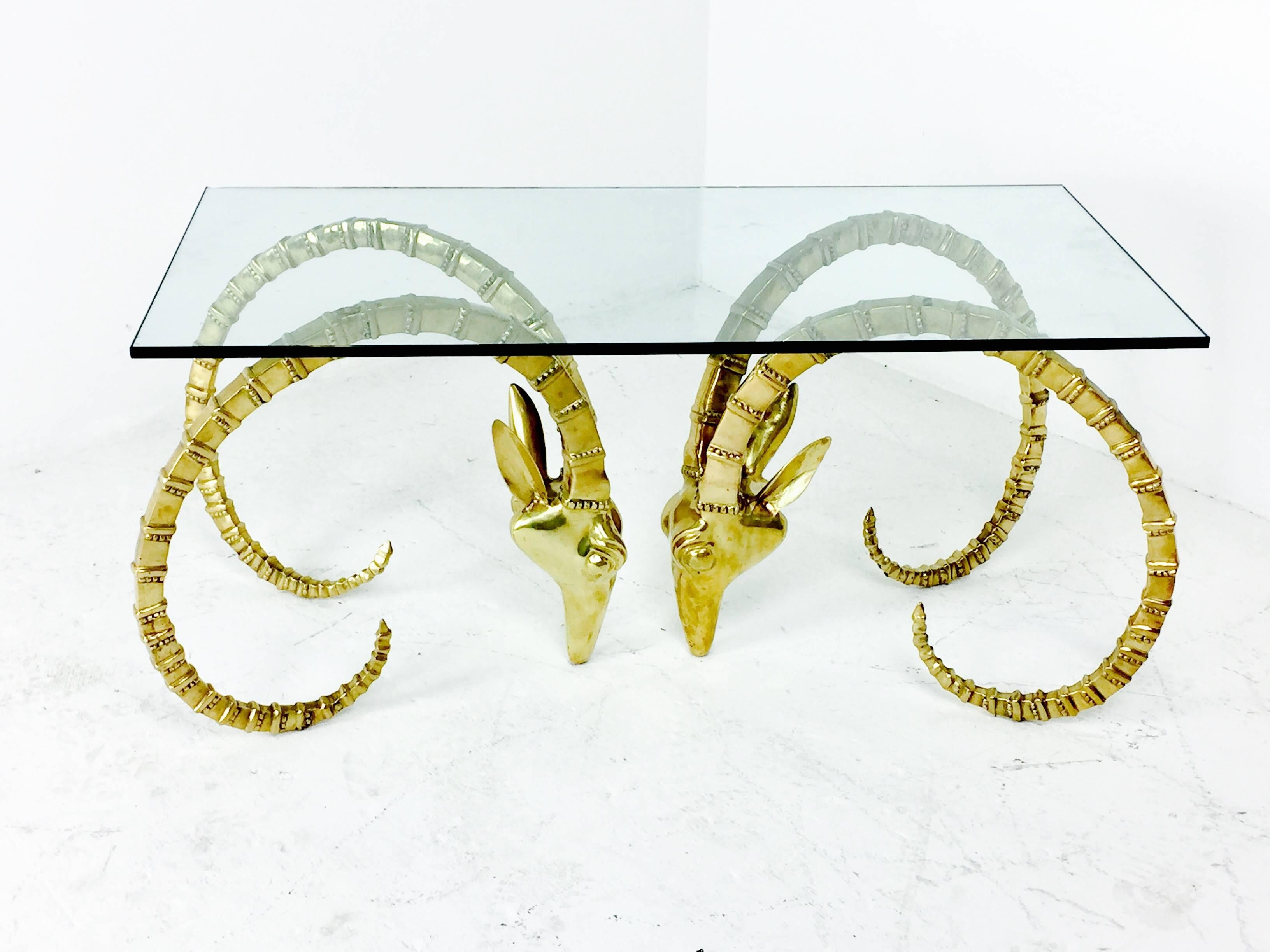 Brass ram's head or Ibex coffee table. Glass top is smaller than normal and has a chip in the glass. New glass is recommended. 

Ram's heads measure 19" W x 22" D x 19" T each,
and glass top is 40" L x 20" D x .5"