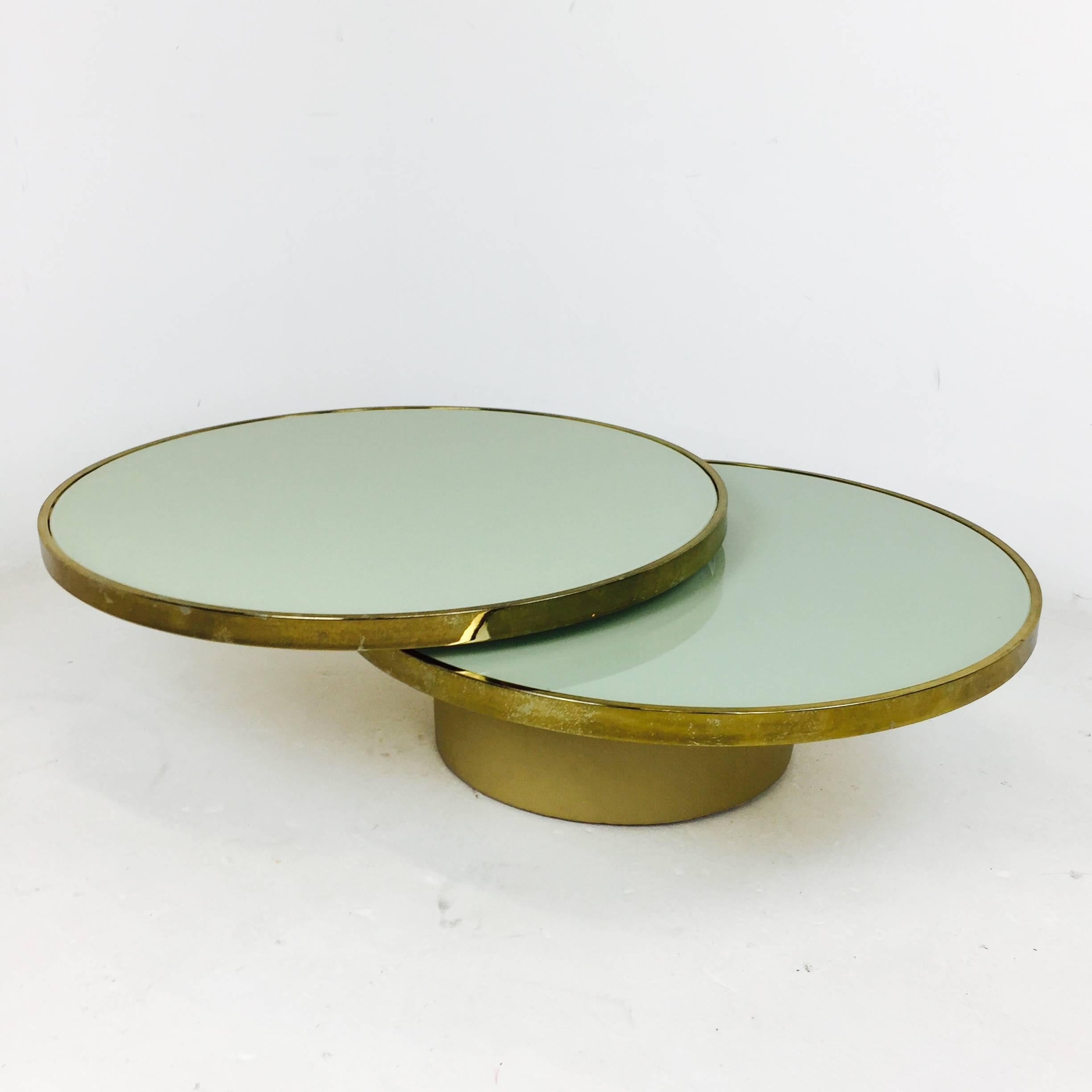 Rotating or swivel brass and frosted glass coffee table by Design Institute of America. The base is covered in cream vinyl. The glass is cracked on the lower portion of the table and the brass needs to be re-plated. 

Dimensions: 36