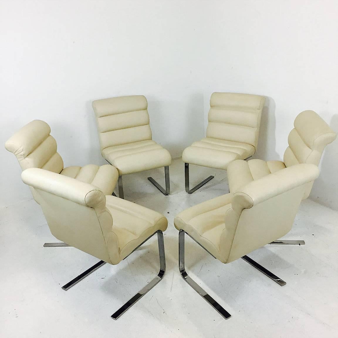 Set of six chrome-plated cantilever dining chairs. Chairs are upholstered in a cream vinyl that does has small rips in a couple of chairs. New upholstery is recommended.

Dimension: 21" W x 27" D x 34" T
seat height 19".