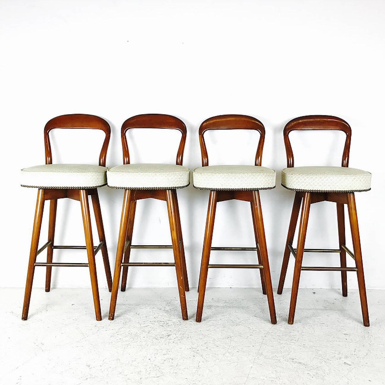 Set of four MCM bar stools in the style of Edward Wormley. Stylish open back bar stools with brass-plated footrest. Stools need refinishing and new upholstery, circa 1960s

dimensions: 17