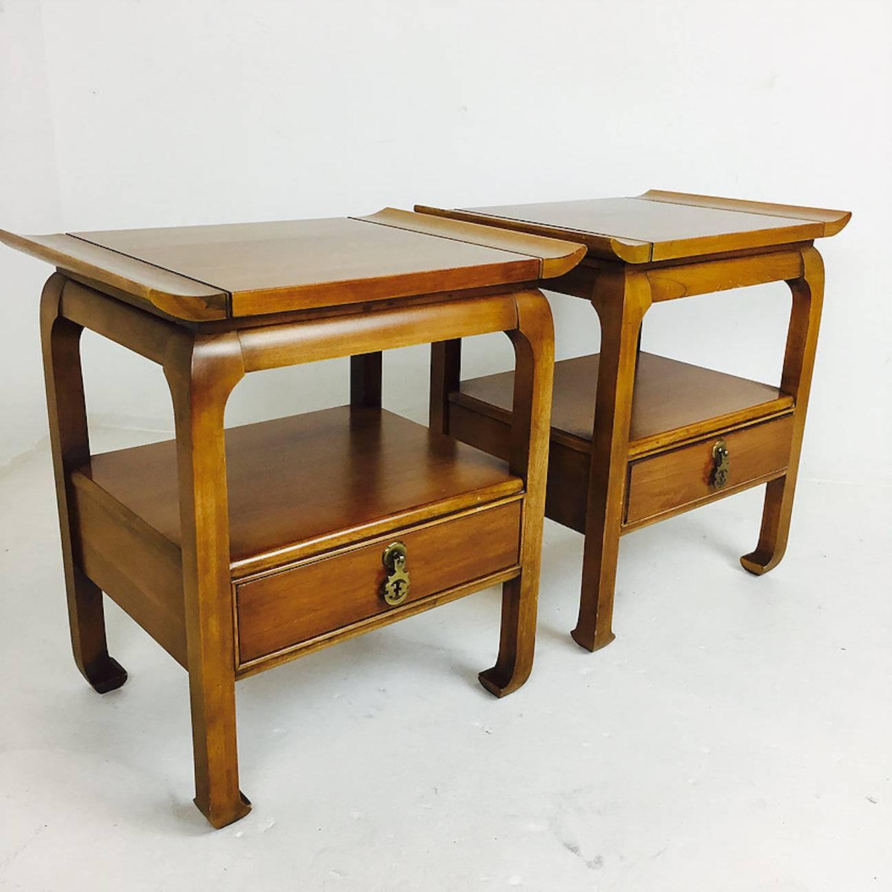 Pair of Mid-Century Pagoda style nightstands/side tables. The nightstands have a patina brass Asian influenced hardware. There is minor visible wear due to age an usage. circa 1960s

dimensions: 24"wide  17"deep  26"tall.