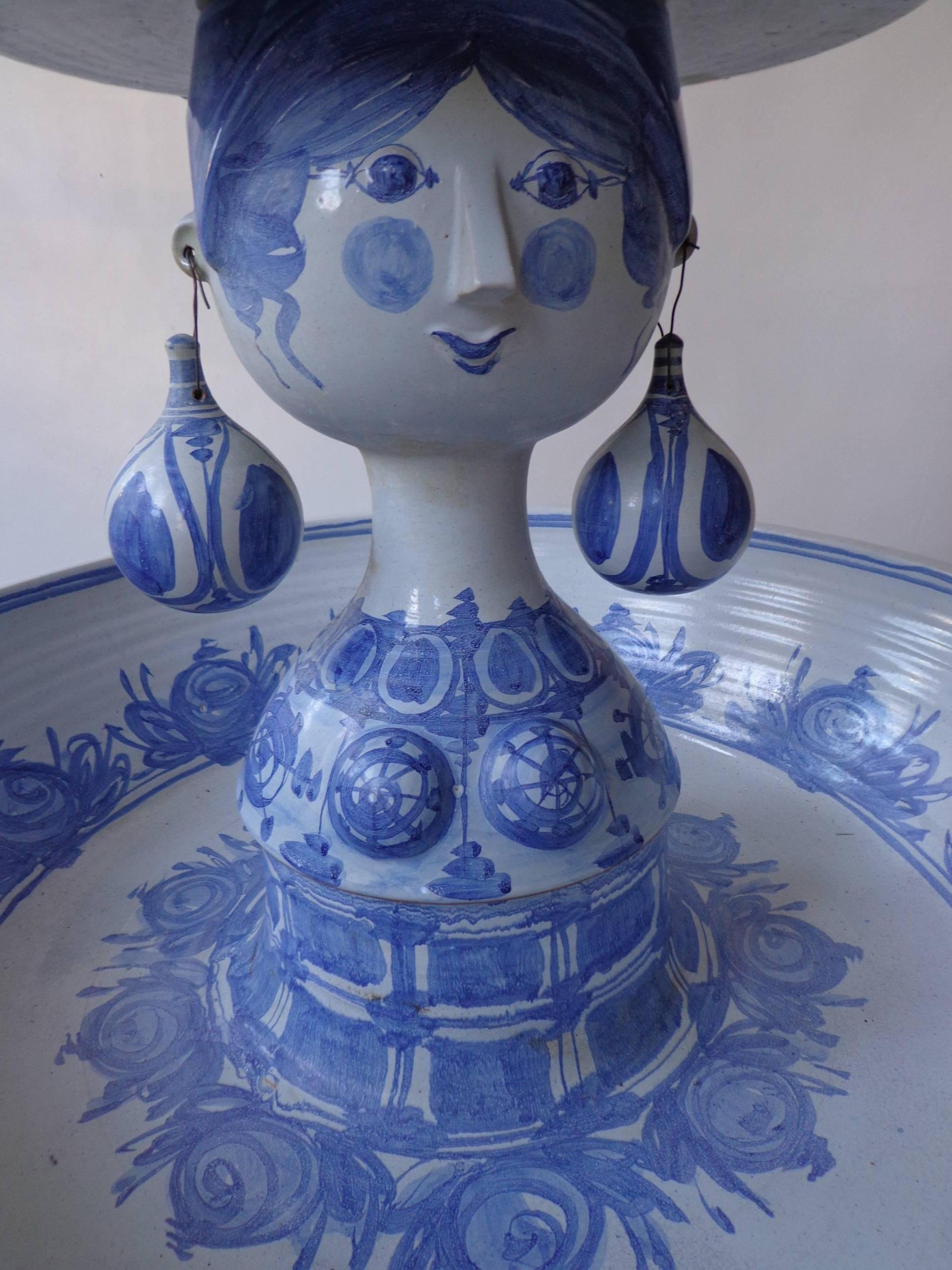 Bjørn Wiinblad, Danish, 1918-2006.
Unique monumental ceramic fountain with blue, white glaze. Woman with hat decorated with earrings and flowers. 
Five pieces: Hat, woman, earrings, vessel and reservoir. Measures: H 120 cm, vessel diameter 80