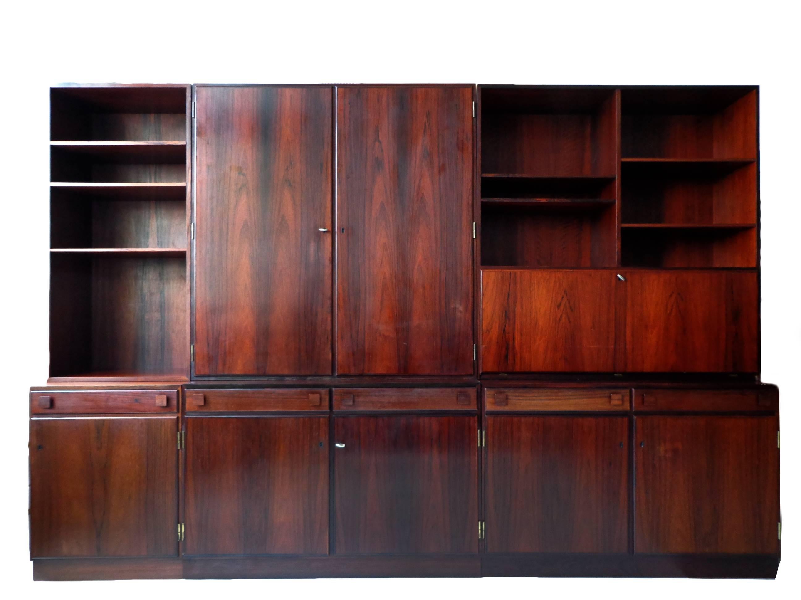 Offerd by Zitzo, Amsterdam: Wall unit of rosewood designed by Takashi Okamura and Erik Marquardsen, consisting of three base cabinets with doors and shelves inside. Three Top cabinets with pullout trays, shelves and drop leaf-desk. Original keys