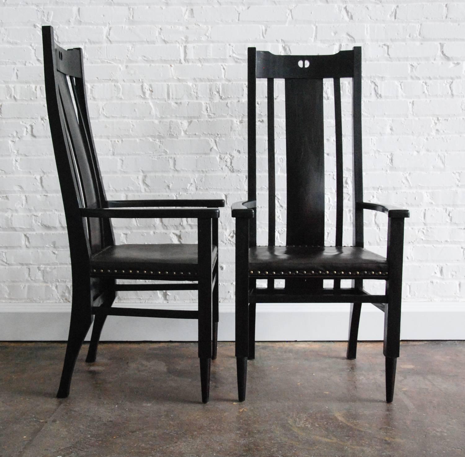 A stunning pair of ebonized oak and leather highback armchairs inspired by the designs of Gustave Stickley, Charles Limbert and Charles Rennie Mackintosh in the Arts and Crafts style updated to the 80's art furniture movement.  The chairs are