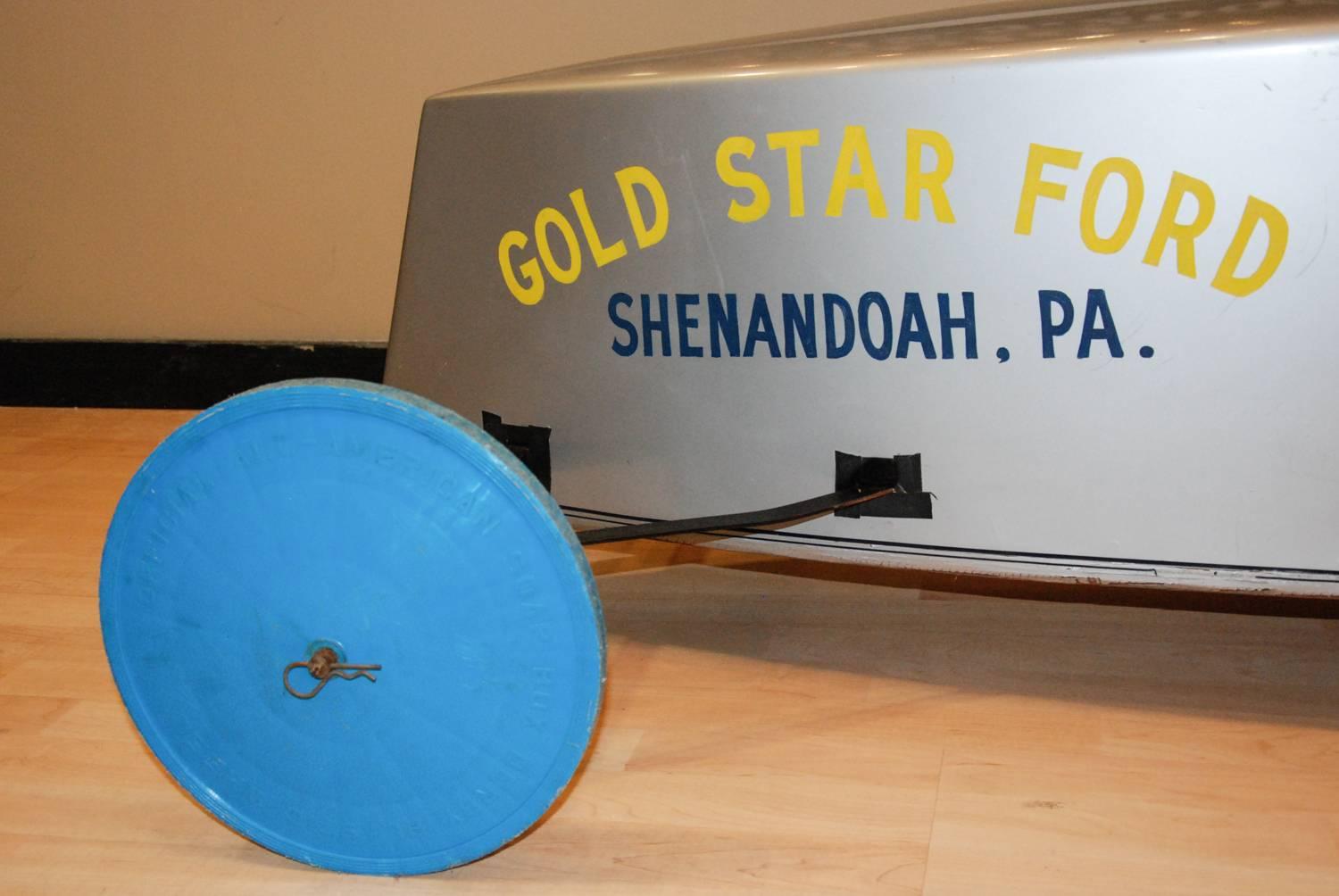 A sleek metallic silver soap box derby car from Shenandoah, Pennsylvania driven by Buzzy Burns.  The car has official All-American Soap Box Derby plastic wheels and Buzzy Burns' red racing helmet with chin strap.  What a great gift for the kid who