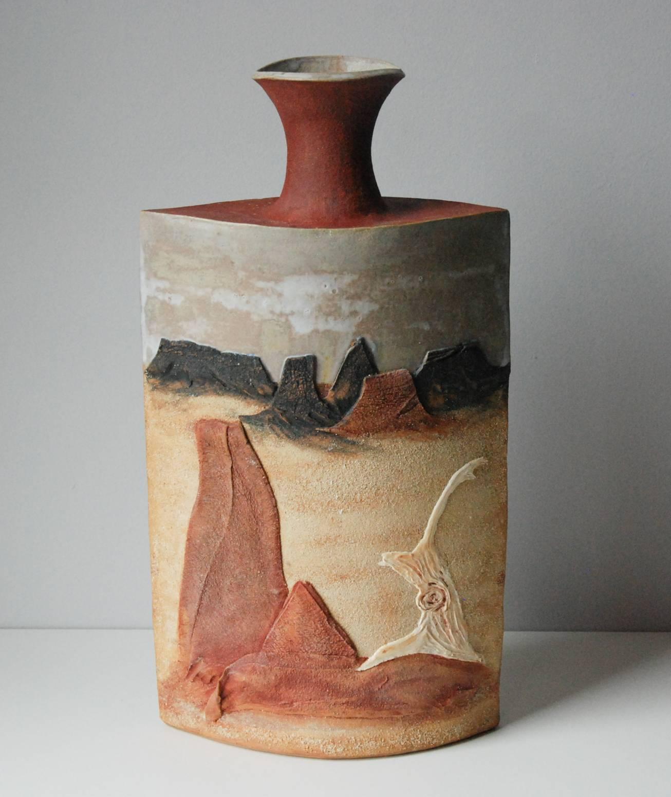 A monumental R. Miller slab built stoneware vase depicting desert sands, plateaus and a sun drenched tree base in relief against a gray desert sky. The work is signed on the lower left corner.