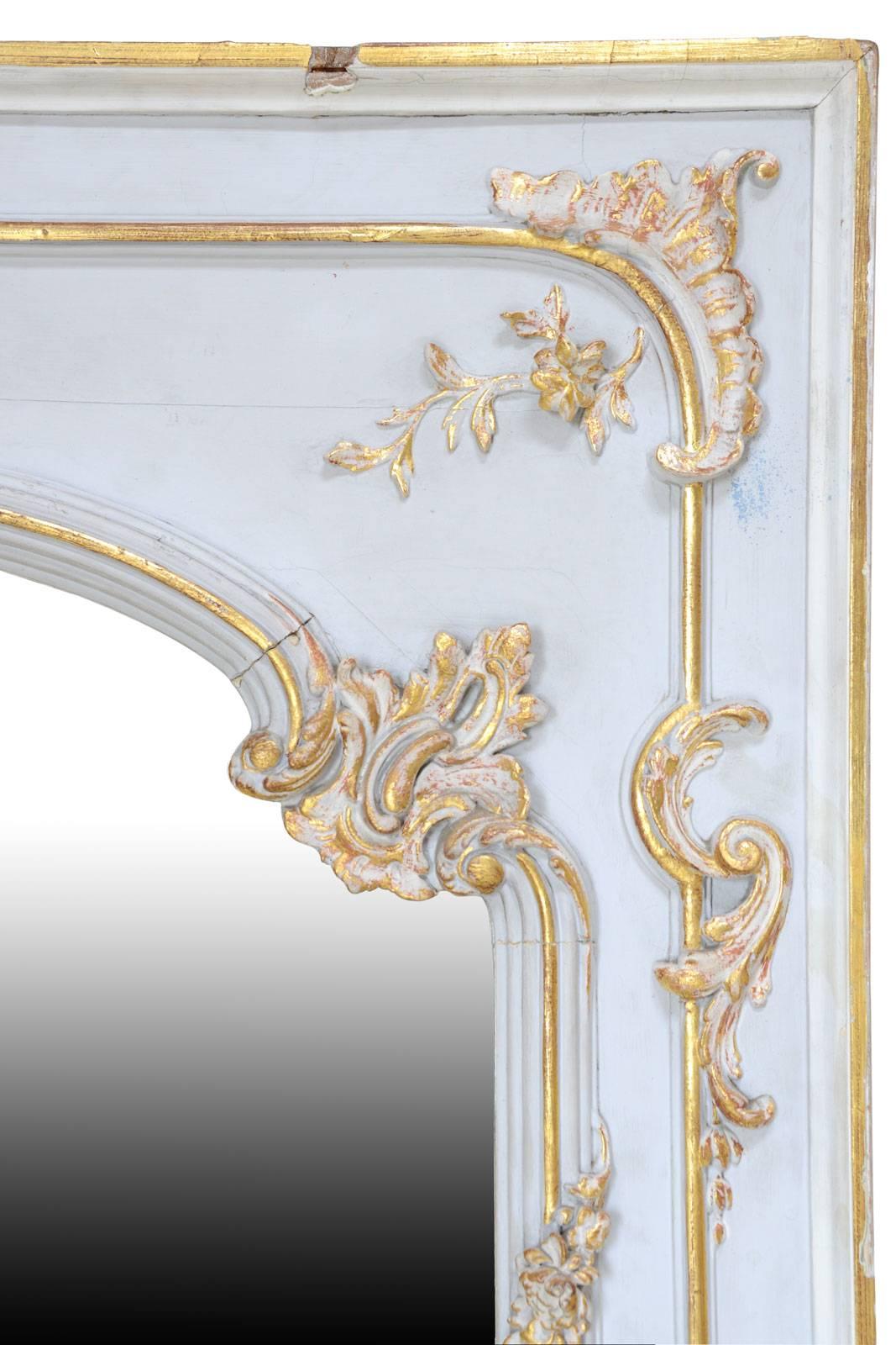 Dating from the 19th century, Louis XV style gilded wood and white rechampi mirror. It is animated with plants motifs and foliage, and a shell overlooks the mirror.