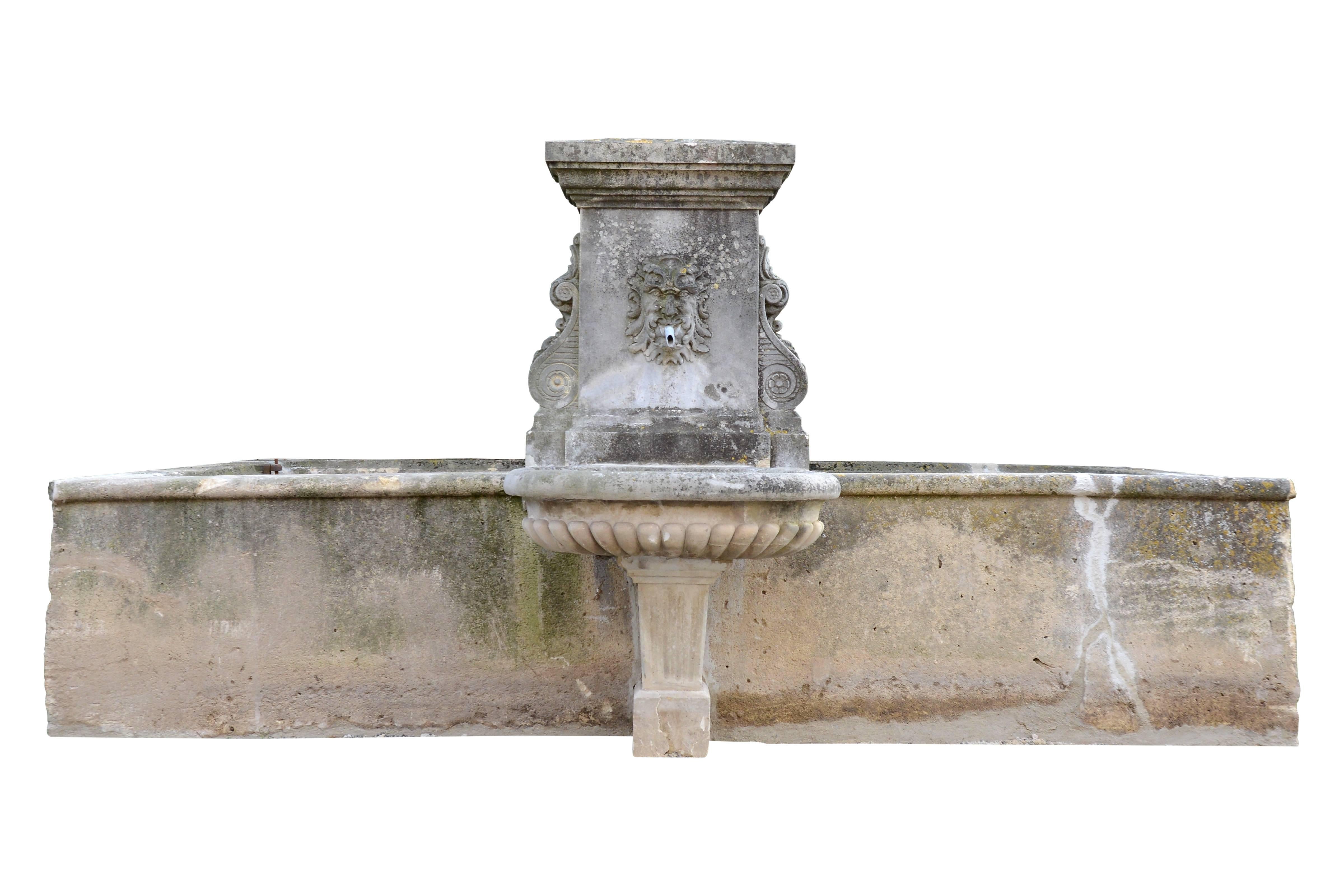 Dated from the early 19th century, circa 1820, Louis XIV style stone basin with fountain backed. The fountain is decorated with windings, shells and flowers from either side of a gadrooned basin topped by a pediment with median Neptun mask and