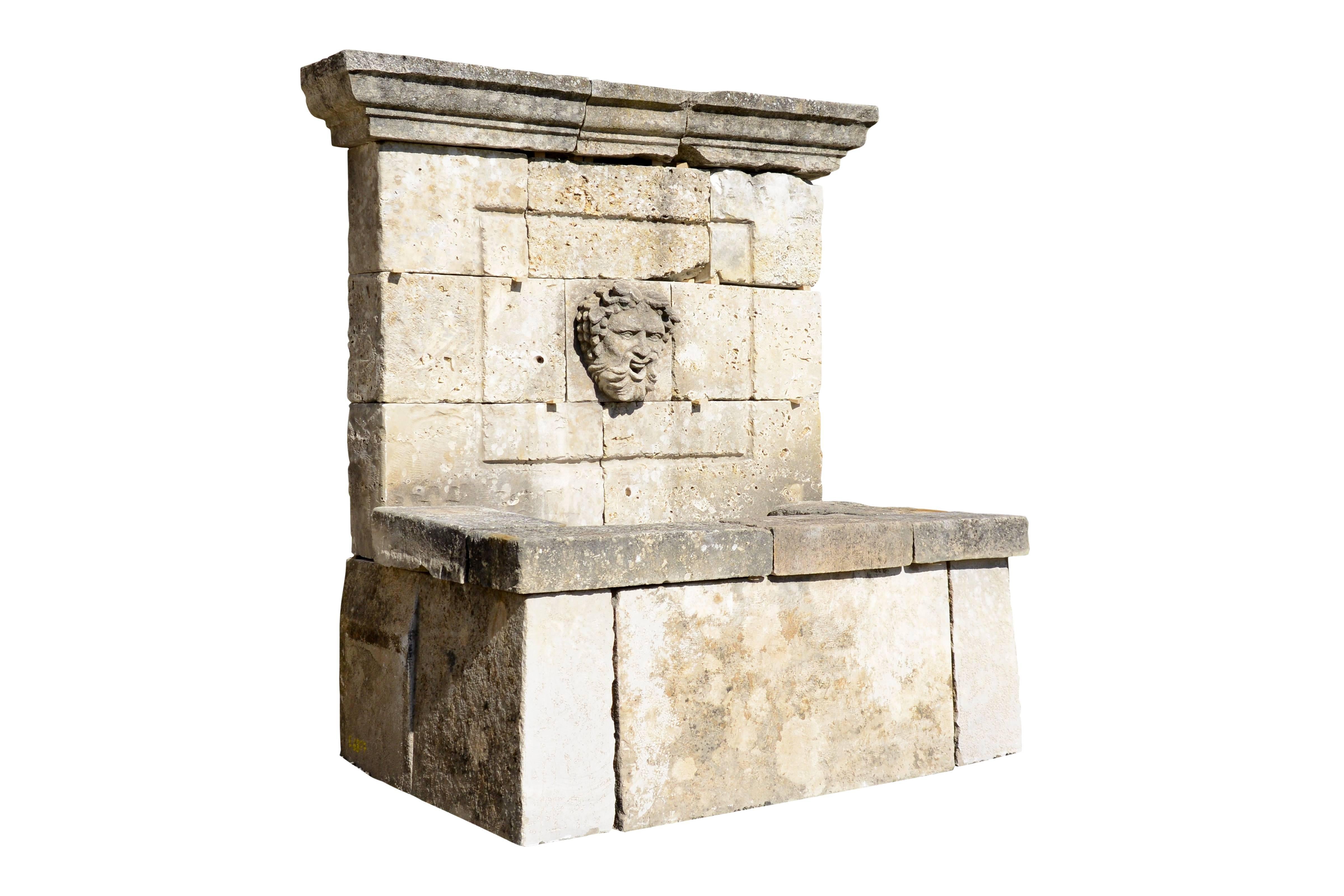 Composition of antique 19th century period reclaimed architectural elements forming a Provençal style wall fountain. The pediment, topped by a degrees cornice, is decorated with a moulded frame within which there is a carved mask.