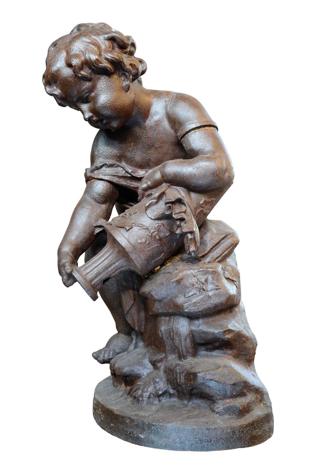 Dated from the 19th century, circa 1880, cast iron fountain center in the image of a putto holding an urn. Draped in the antique, the putto is represented holding an urn whose he seems to let flow water, amidst vegetal elements. Foundry stamp on the