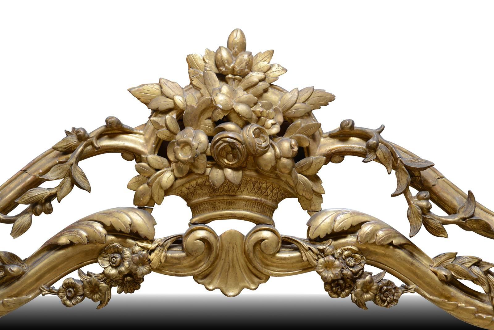 Dated from the end of the 19th century, Regence style mirror in wood and gilded stucco. Falls of flowers and foliage winding around the wands that decorate the mirror on both sides. A flowery basket overhangs the ice.