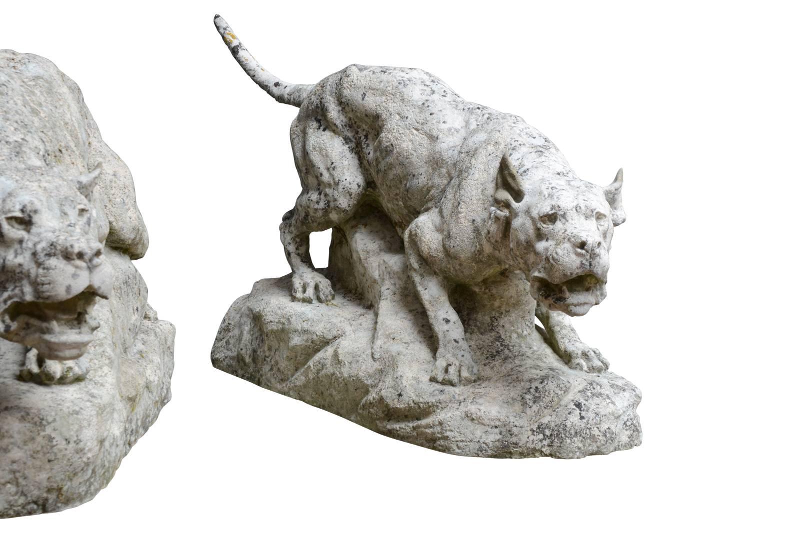 Dated from the early 20th century, circa 1910, imposing stone pair of dogs carved by Thomas François Cartier (1879-1943). This group presents two dogues growling, each wearing a large leather collar and showing the fangs. Signed T