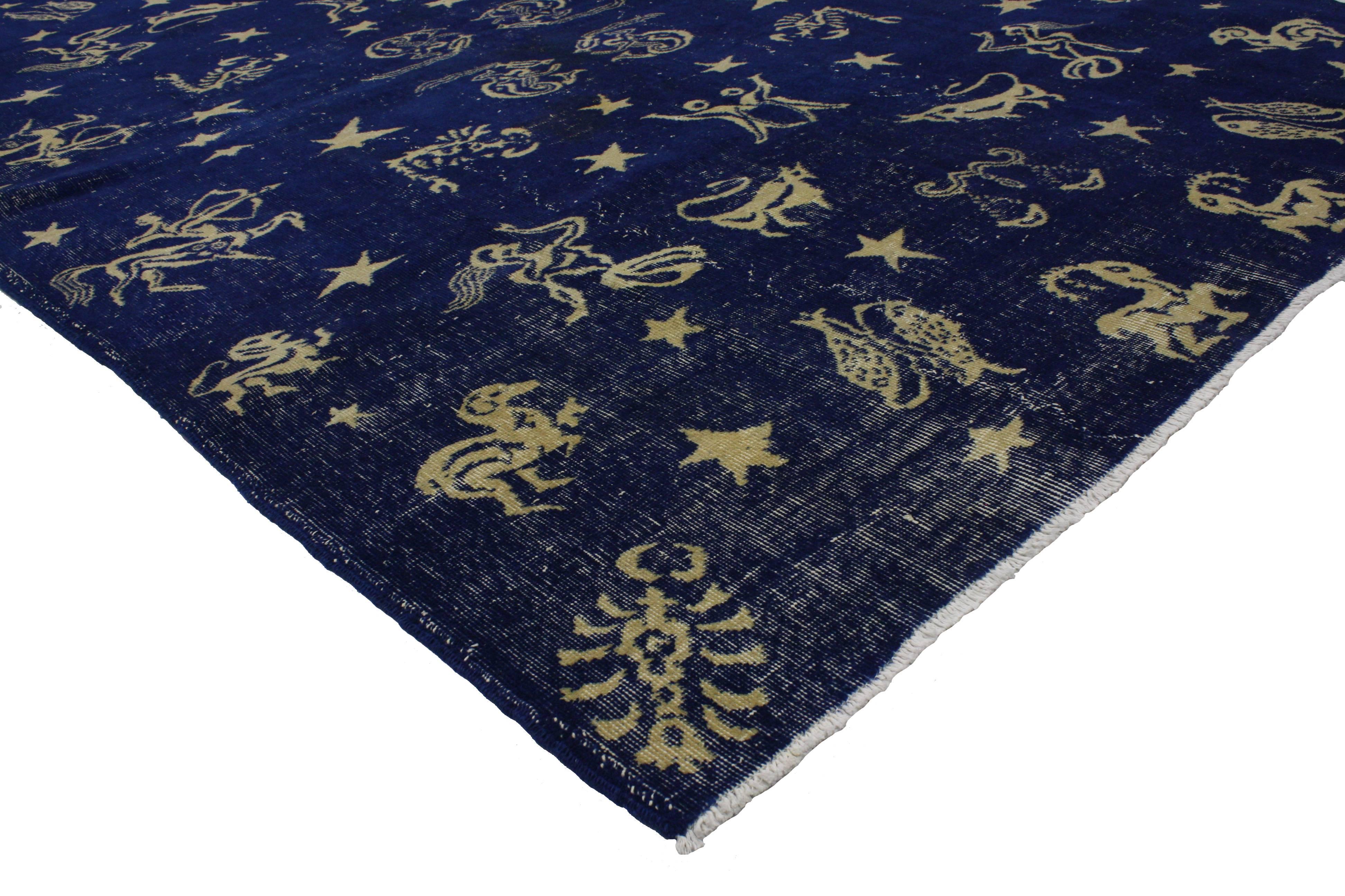 Full of whimsy and astrological symbolism, this distressed vintage Turkish Sivas zodiac rug features a modern Industrial style. Saturated in an extraordinary palette of midnight navy blue with beige motifs, this zodiac rug showcases exquisite