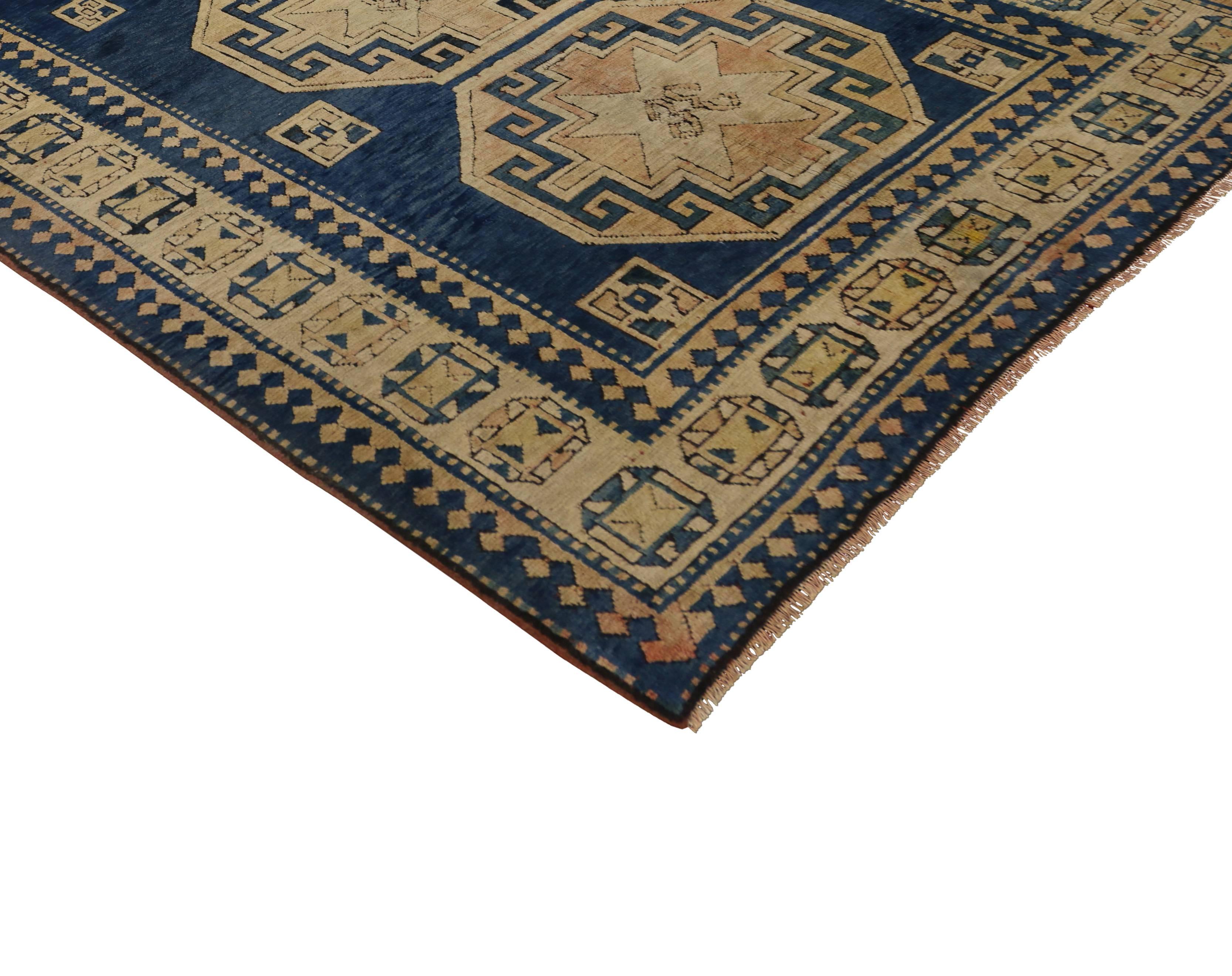 Vintage hand-knotted wool Turkish Kazak rug featuring a triple medallion on an open abrashed blue field surrounded by a geometric border. From warming up modern interiors and adding panache to formal areas, this Kazak rug seamlessly blends with