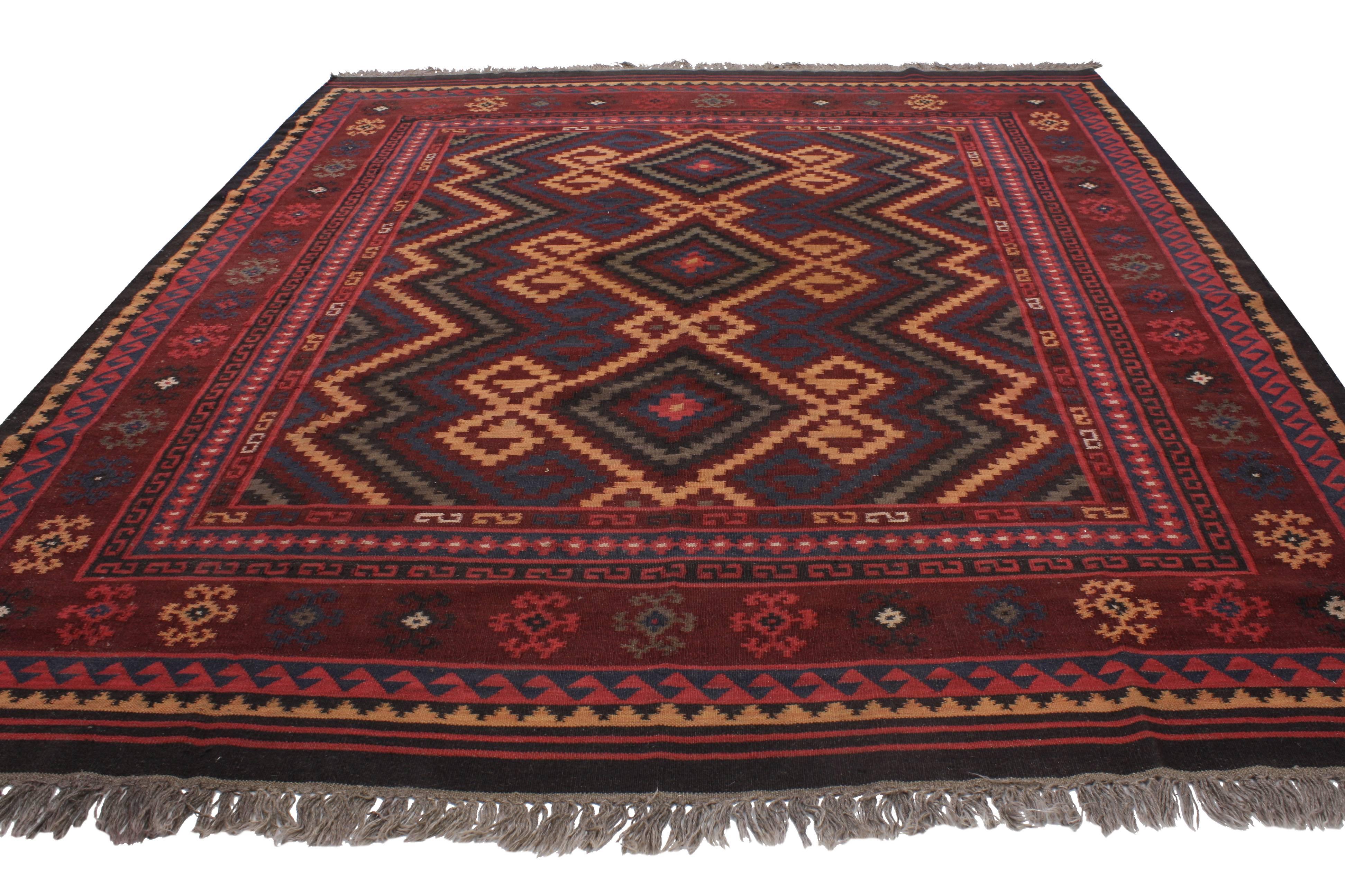 Boasting a stunning tribal design and modern style, this boho chic vintage Turkish Kilim rug shows its age beautifully. This hand-woven wool vintage Turkish Kilim rug features three stacked diamonds, each flanked with ram horn motifs surrounded by