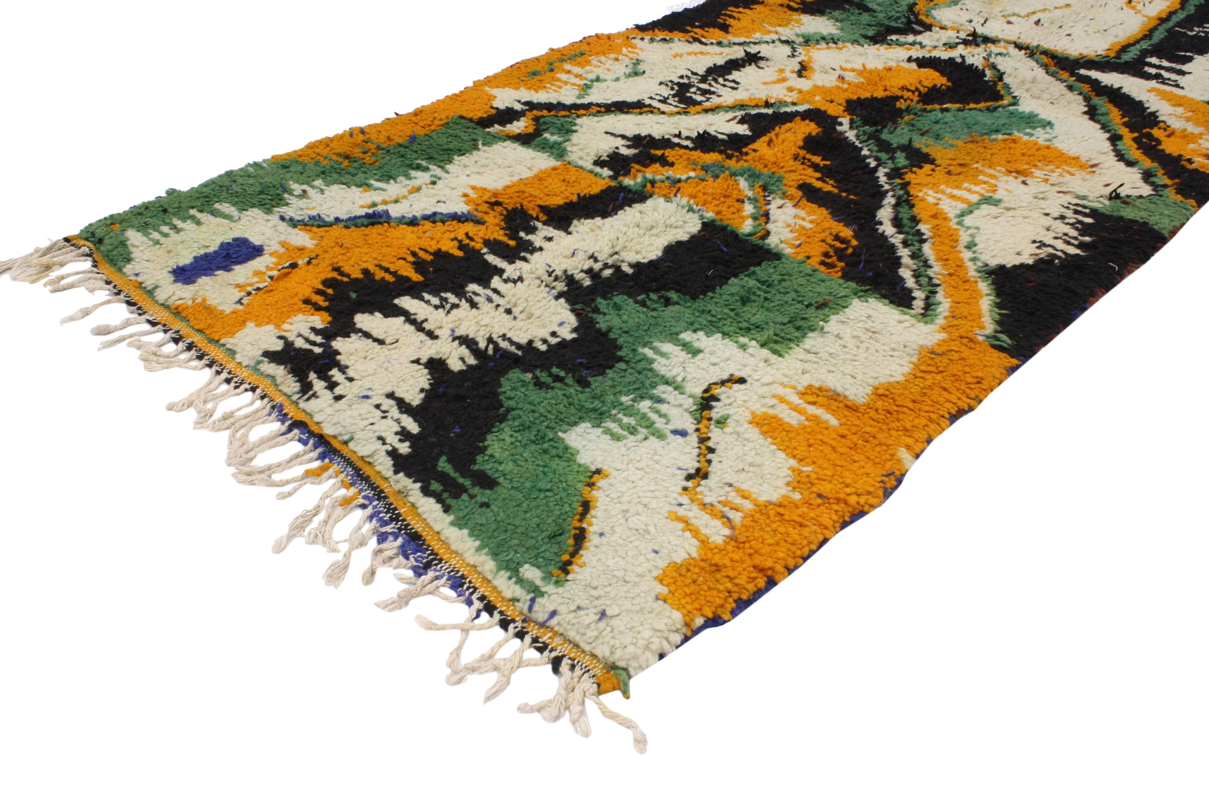 This hand-knotted wool vintage Berber Moroccan rug features an all-over contemporary abstract design. Rendered in green, orange, black and ivory-beige with a hint of blue and brown. With its contemporary and abstract design, this Berber Moroccan rug