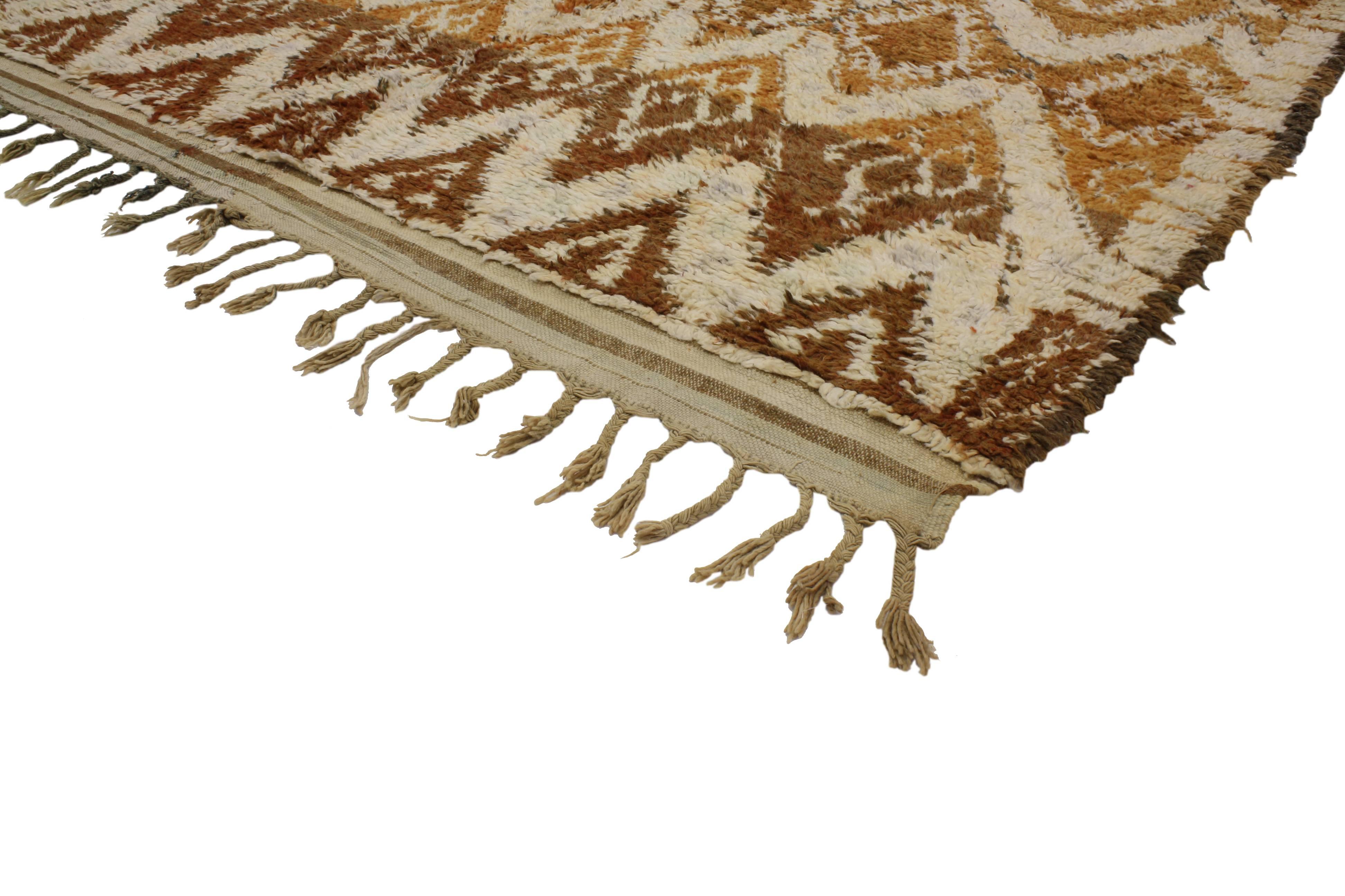 This vintage Berber Moroccan rug features Mid-Century Modern style. Rendered in variegated shades of brown, rust, saffron gold, beige and cream. Displaying a unique repetitive and random diamond pattern. With its plush pile from hand-knotted wool,