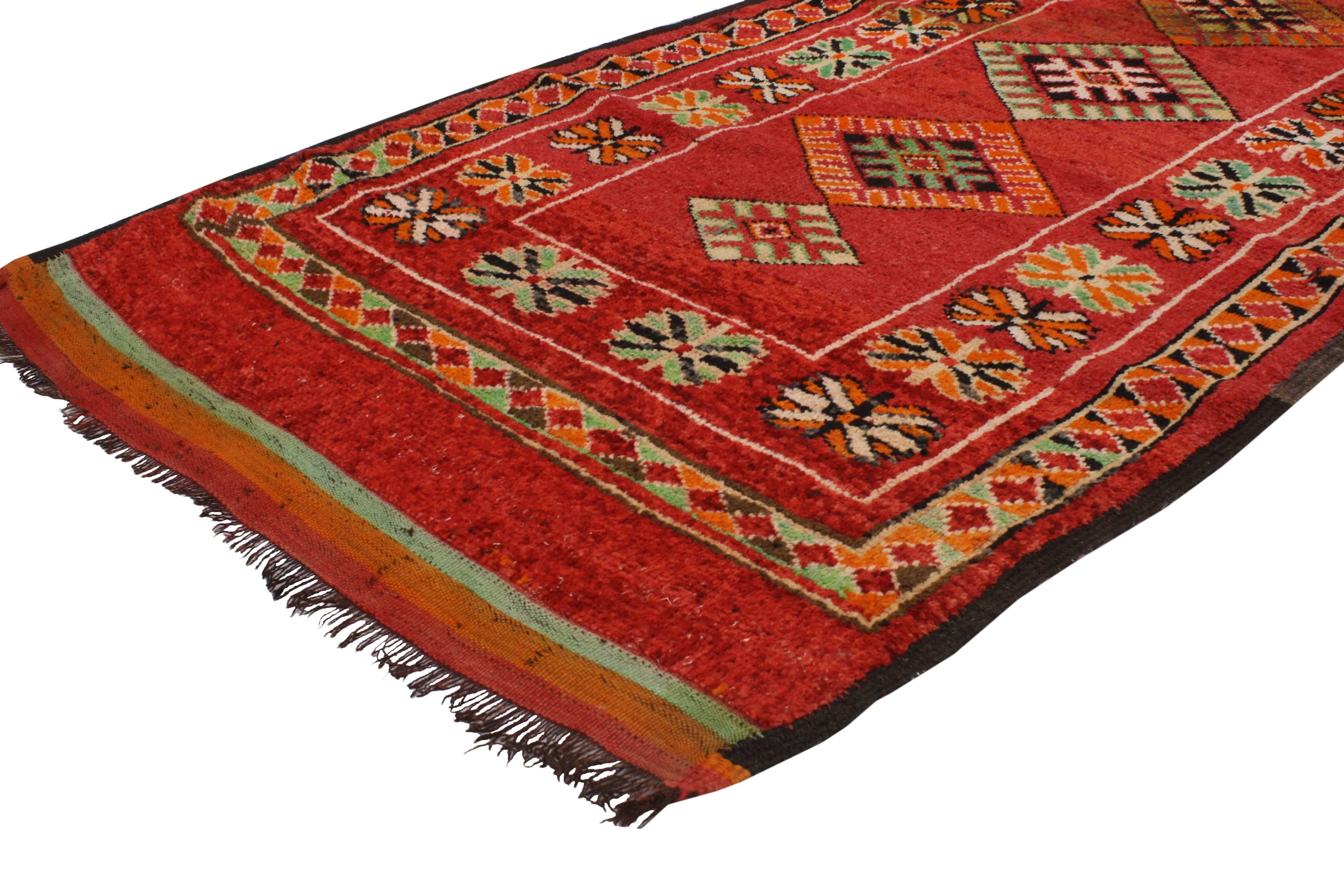 Impeccably woven from hand-knotted wool and displaying a modern tribal style, this vintage Berber Moroccan red rug features four stacked diamonds surrounded by geometric motifs in an abrashed red field. Blending the graphic appeal and Folk Art