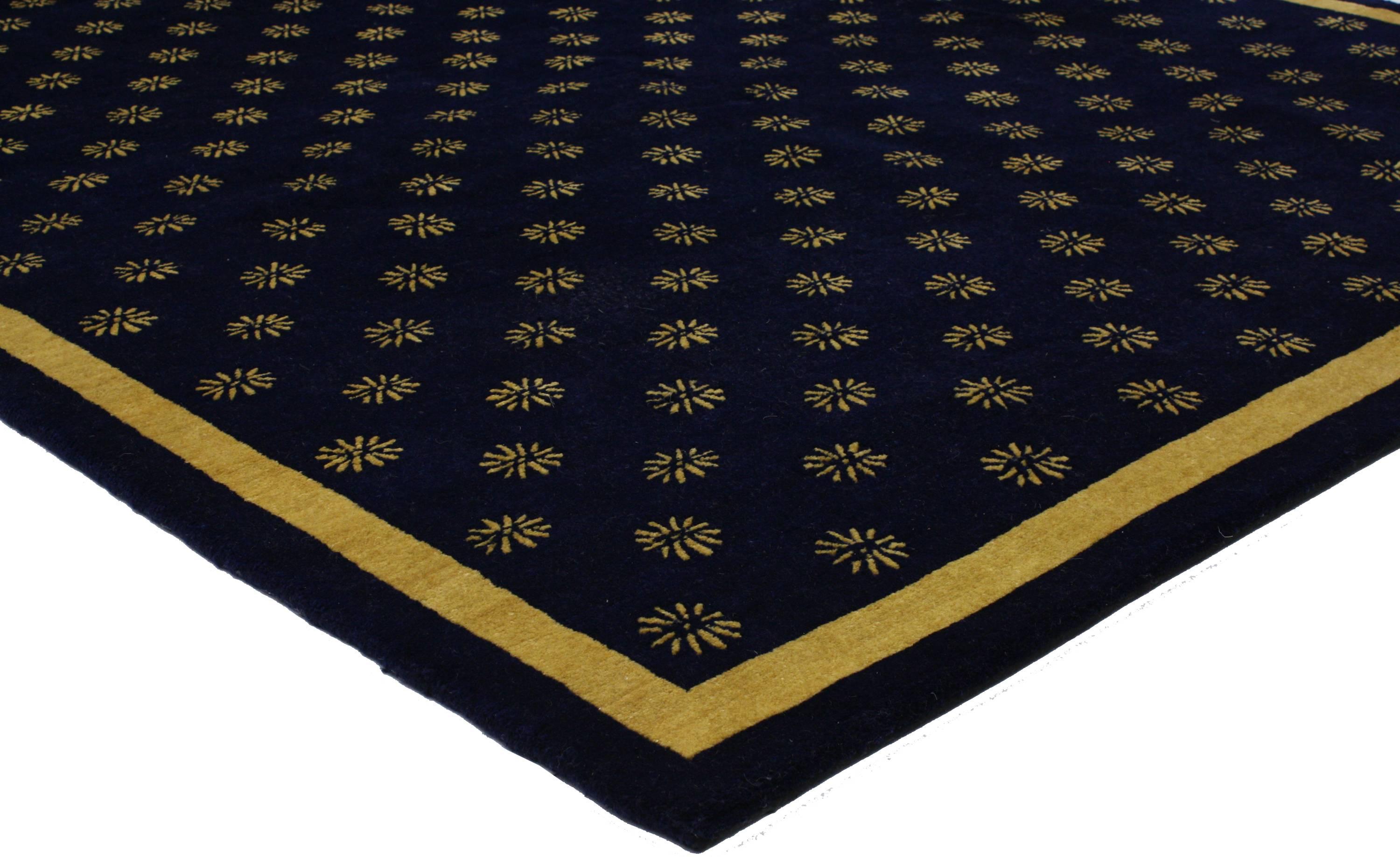 This navy blue and gold area rug features a Hollywood Regency style. Highlighting an all-over pattern of gold motifs on a navy blue background, this transitional rug exudes sophistication with a hint of swagger and a twist of neoclassical glamour.