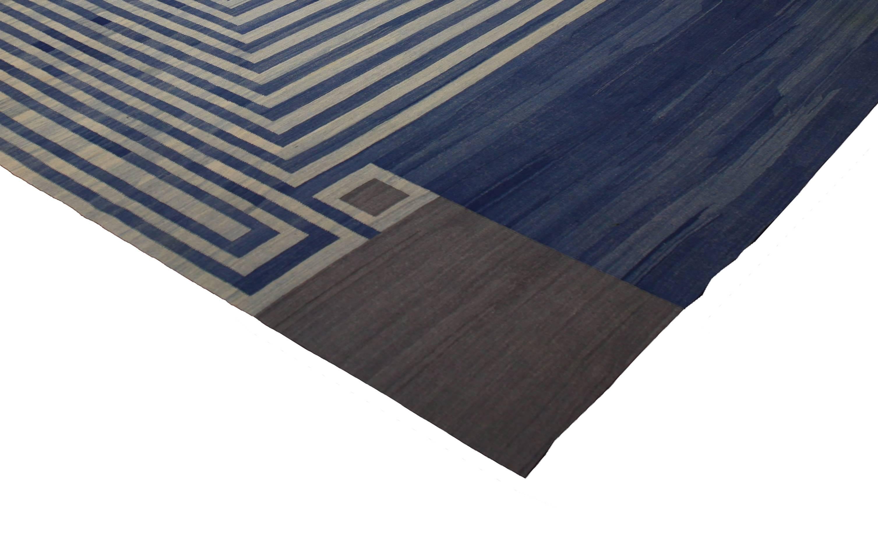 Causal and calm or bold and Bohemian, this vintage Afghani Kilim rug features a Mid-Century Modern style. This flat-weave Kilim rug showcases a creamy beige square with alternating blue stripes. Rendered in variegated shades of blue, grey and