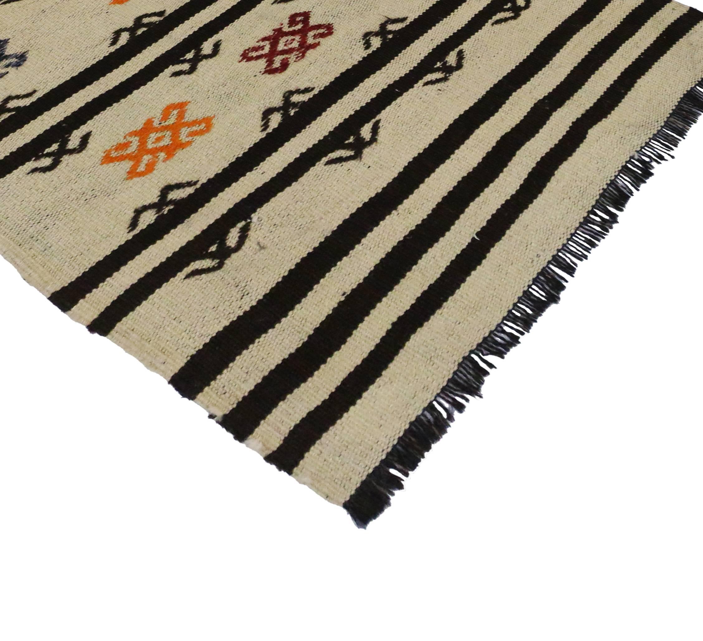 Highlighting the finest trends in design, this Boho chic vintage Turkish Kilim with stripes and modern Tribal style. Features black stripes and color Turkish motifs on a creamy-beige field. A fine example of simplicity and universal appeal, this