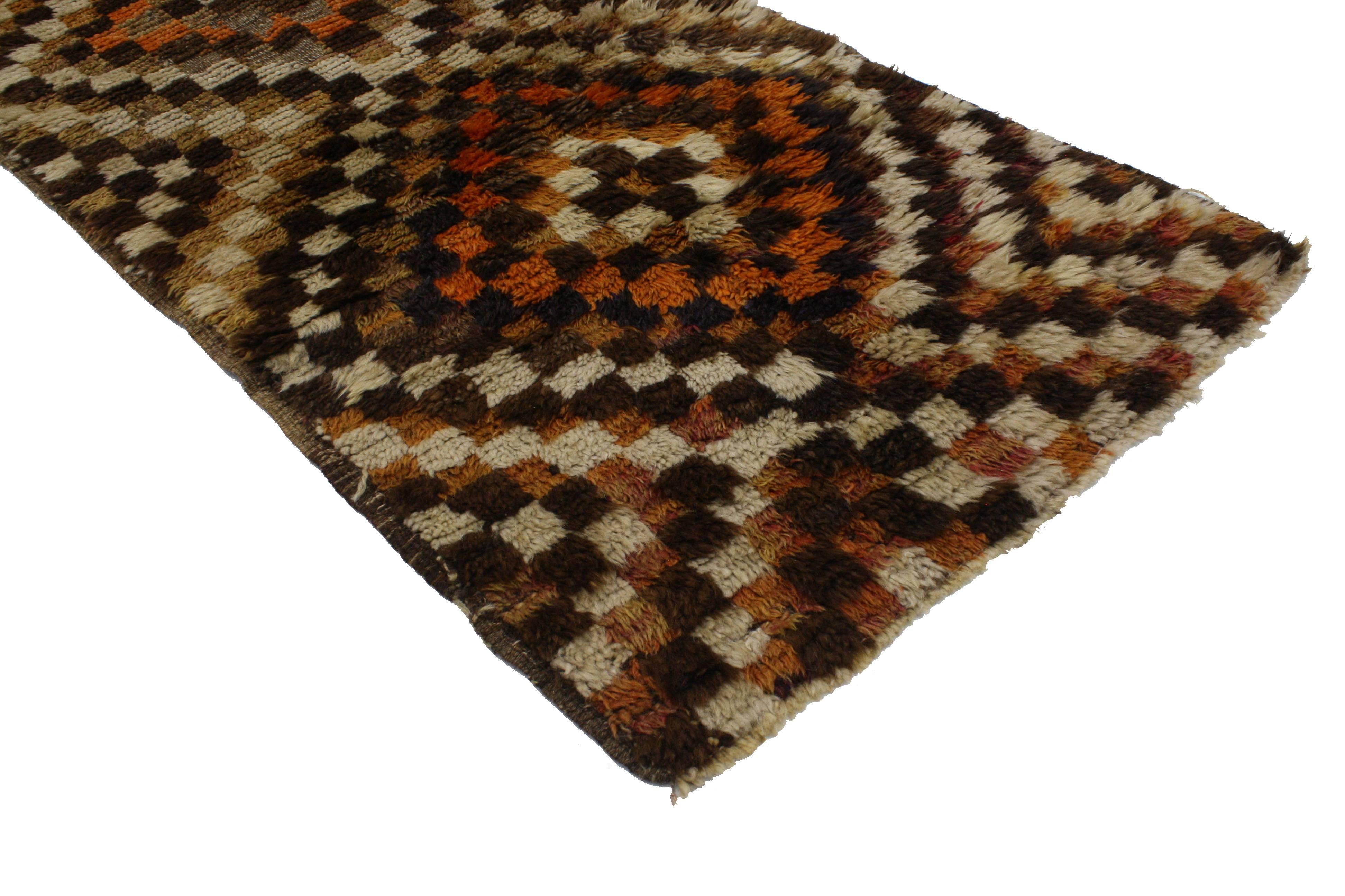With its Primitive charm and checkered pattern, this Mid-Century Modern vintage Turkish Tulu runner synthesizes beautifully with modern architecture. Alternating blocks of warm earth tones form an all-over checkerboard pattern. While the simplistic