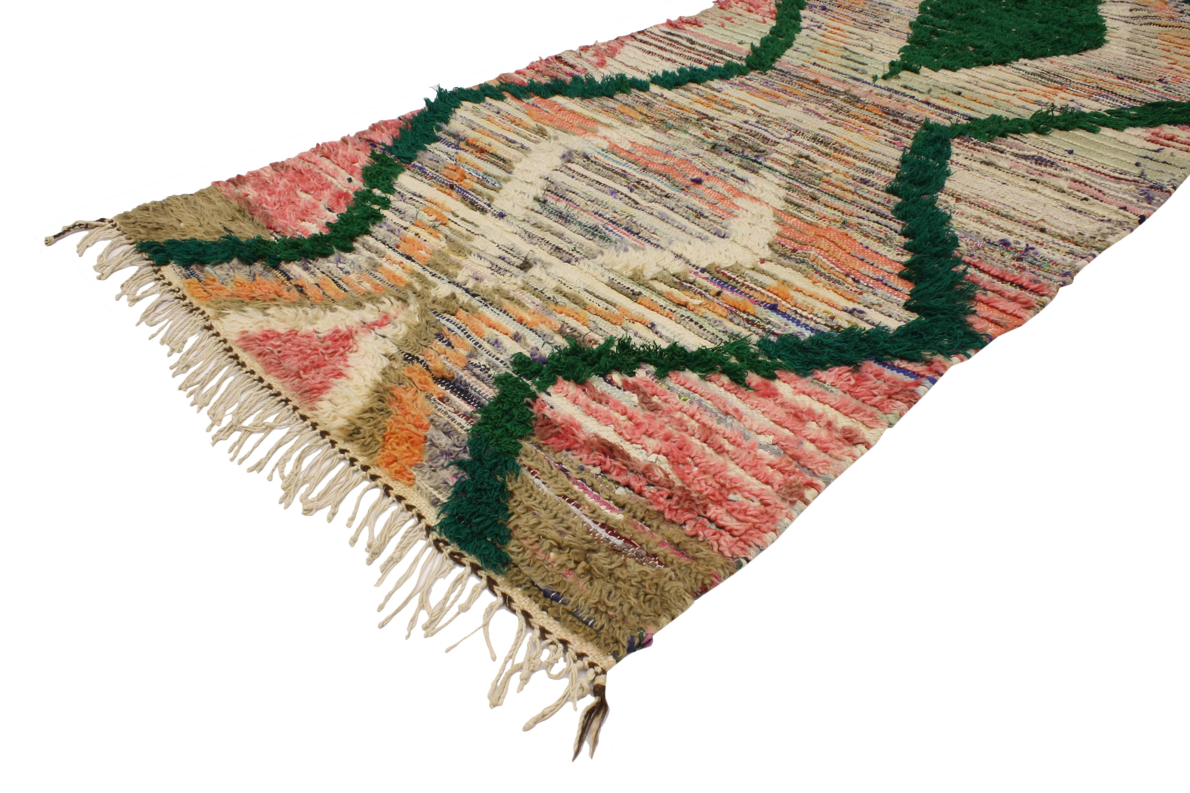 This boho chic vintage Berber Moroccan runner features a tribal design. Highlighting a row of stacked diamonds surrounded by a green zigzag vertical border. The outer zigzag lines referred to as snakes symbolize male potency. The stacked diamond