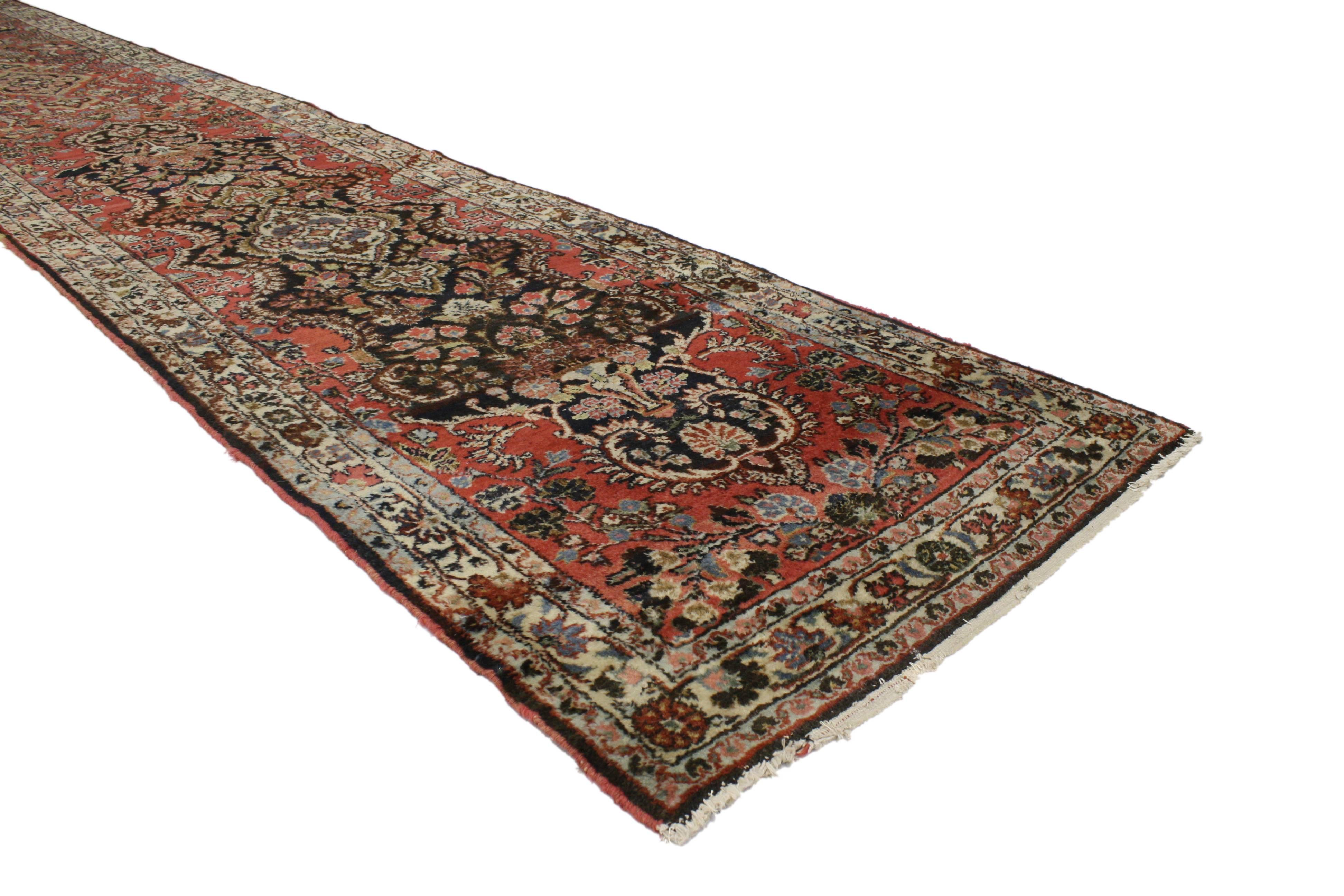 Impeccably woven combined with its bold elemental nature, antique Persian Hamadan extra long carpet runner embodies traditional style. Two black cartouche style medallions are placed in a red field surrounded by florals. The meticulously