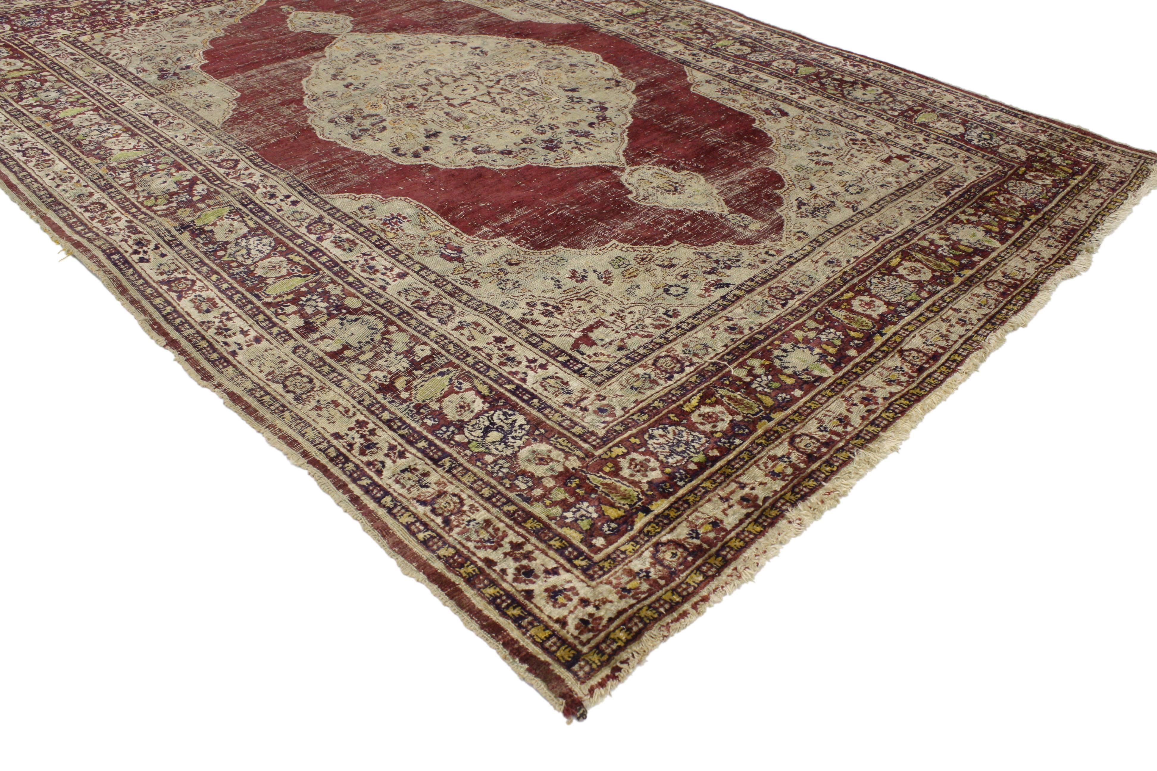 76953 Distressed Vintage Persian Silk Tabriz Rug with Modern Industrial Style. This charming vintage Persian silk Tabriz rug features a grand medallion with two cartouche finials in a red field surrounded by complementary spandrels and equally
