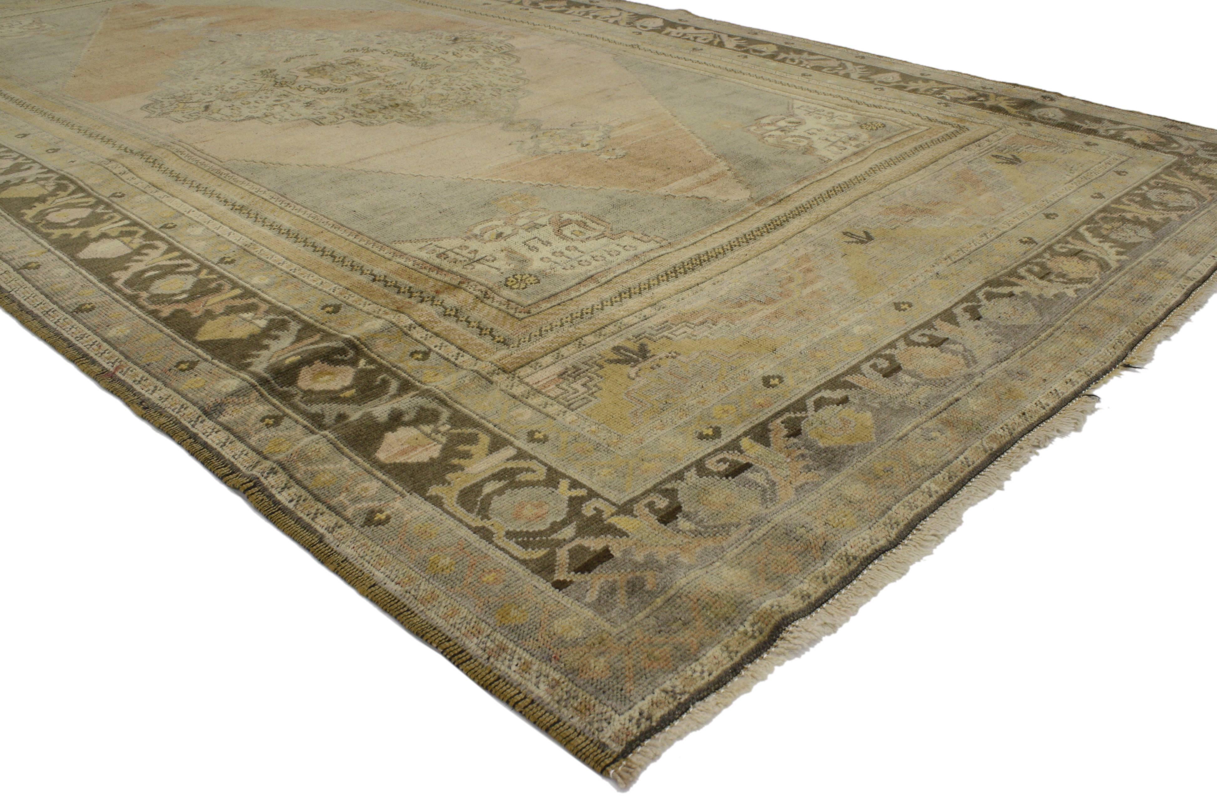This vintage Turkish Oushak carpet gallery rug runner with muted colors features a centre medallion and geometric motifs with a modern traditional style. Rendered in a low-contrast muted colors: rust, gray, ash, brown, beige, sand, apricot, gold,