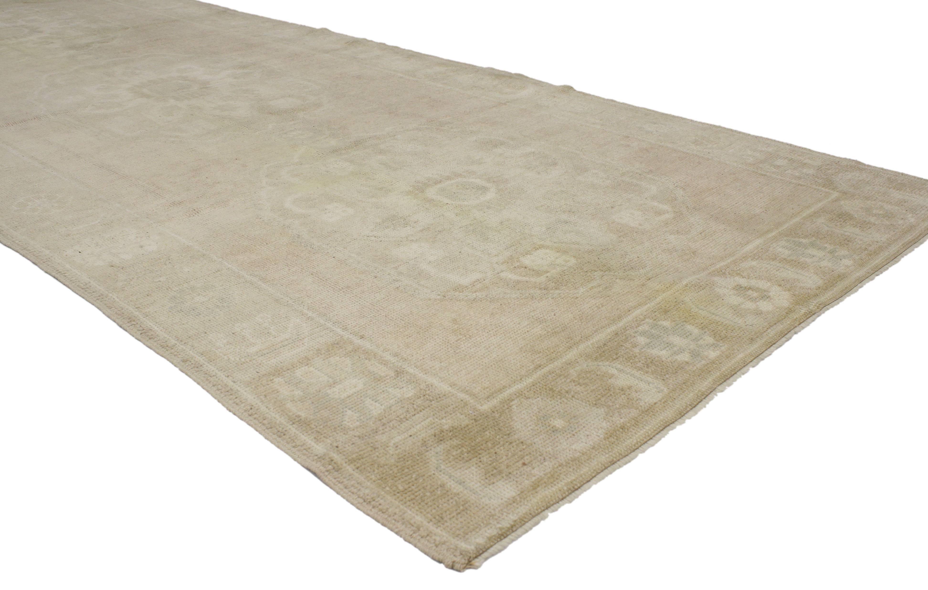 This vintage Turkish Oushak runner comes in muted colors and a casual elegant style. Immersed in Anatolian history, this vintage Oushak carpet runner features three inconspicuous medallions and in an open beige field surrounded by delicate border.