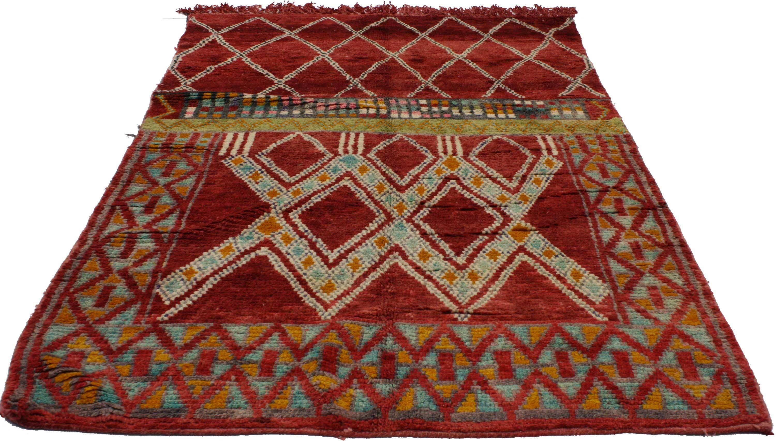 Moroccan rugs are notable for their dynamic colorful designs and for their strong sense of geometric structure. This Mid-Century Modern Moroccan rug features an array of vibrant colors that contrast beautifully on an energetic red background. With