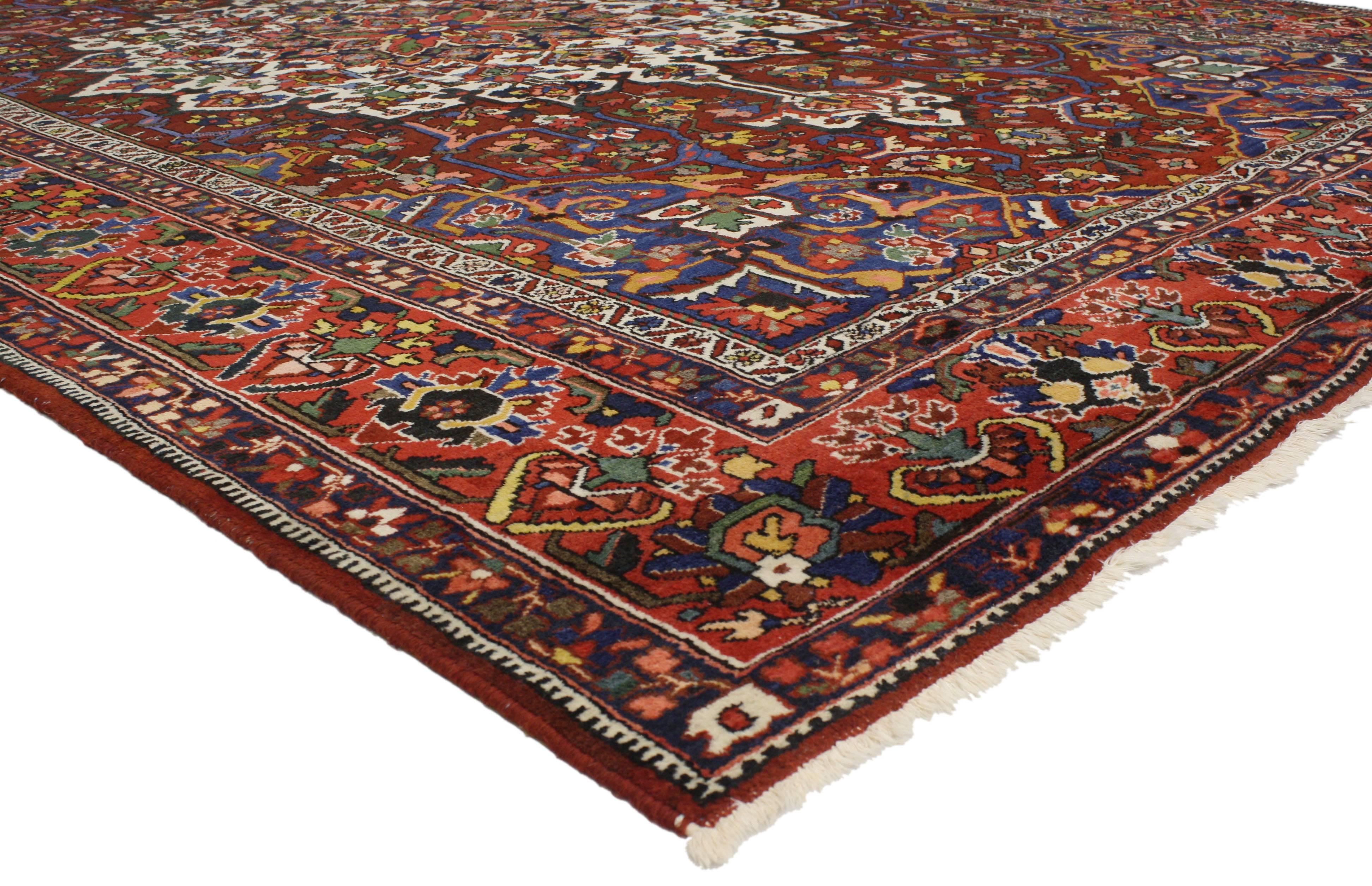 Plein de caractère et très décoratif, cet ancien tapis persan Bakhtiari de style traditionnel moderne présente un médaillon central élaboré et des écoinçons ornés entourés de motifs géométriques. Sur un champ majestueux d'un rouge profond et un