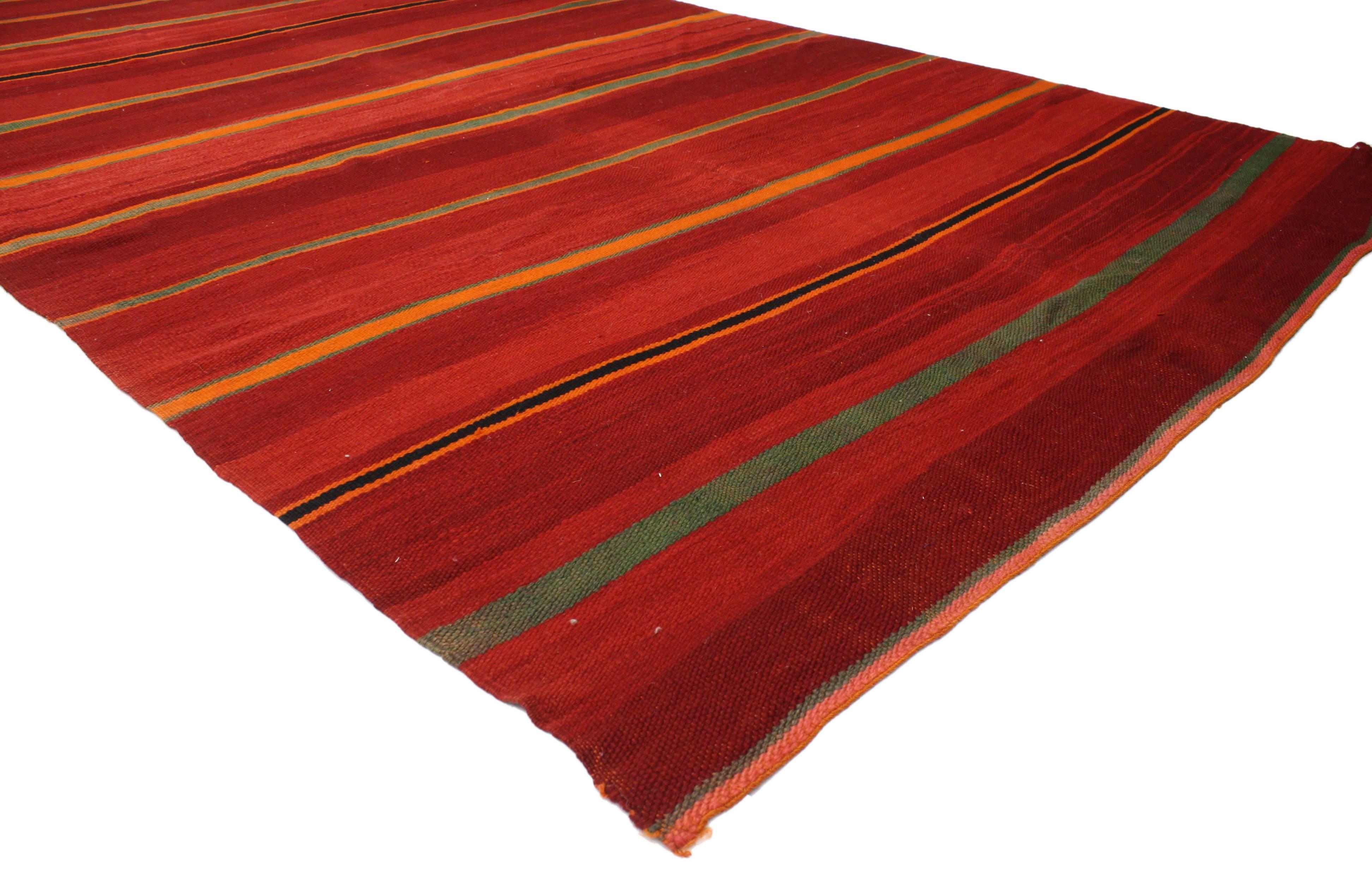 This vintage Berber Moroccan Kilim features a tribal boho chic style, yet it still reflects an understated appearance ideal for modern and contemporary interiors. A series of vibrant colored bands add intrigue and a casual design aesthetic. Rendered