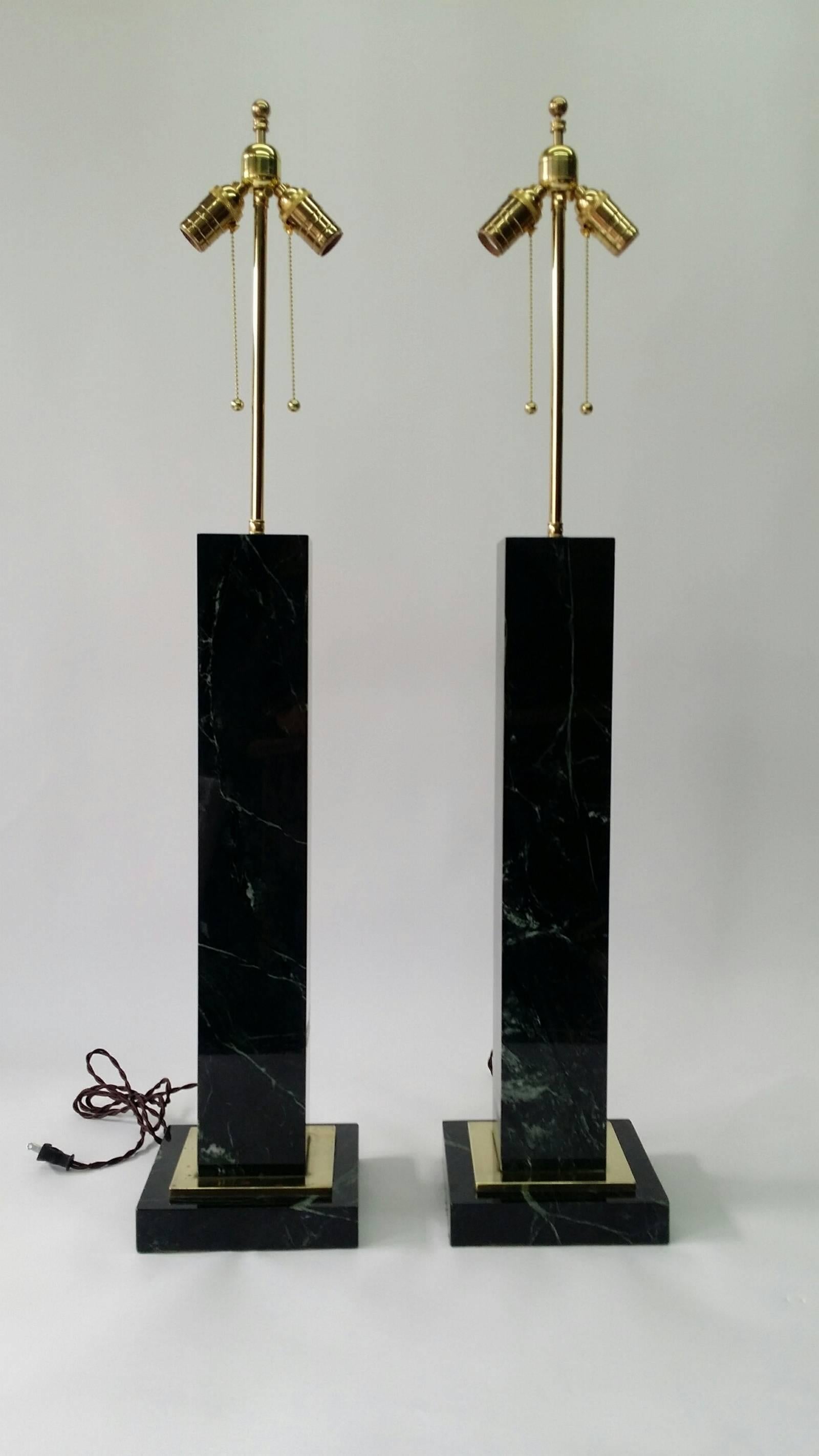 Monumental pair of table lamps made from solid Vermont Verde green marble, circa 1940s. The lamps have solid brass accents on the bases and stand 42 inches tall. They are 8 inches wide at the bases. Fully rewired, including cloth wrapped cords, and