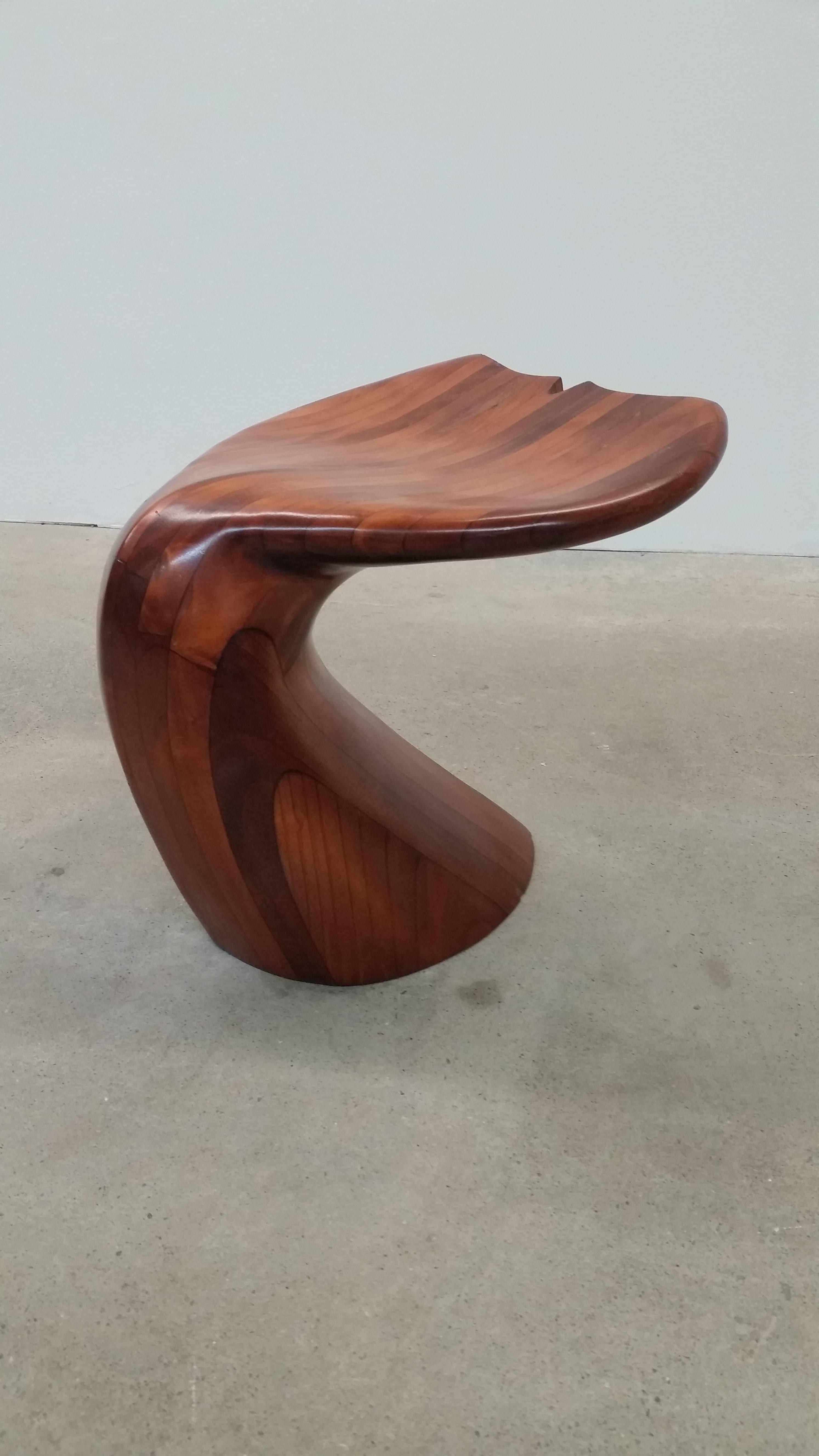 A vintage whale tail form stool, constructed out of laminated blocks of wood, and then sculpted into shape using rasps, and other woodworking tools. A technique popularized by furniture maker Wendell Castle, among others.
