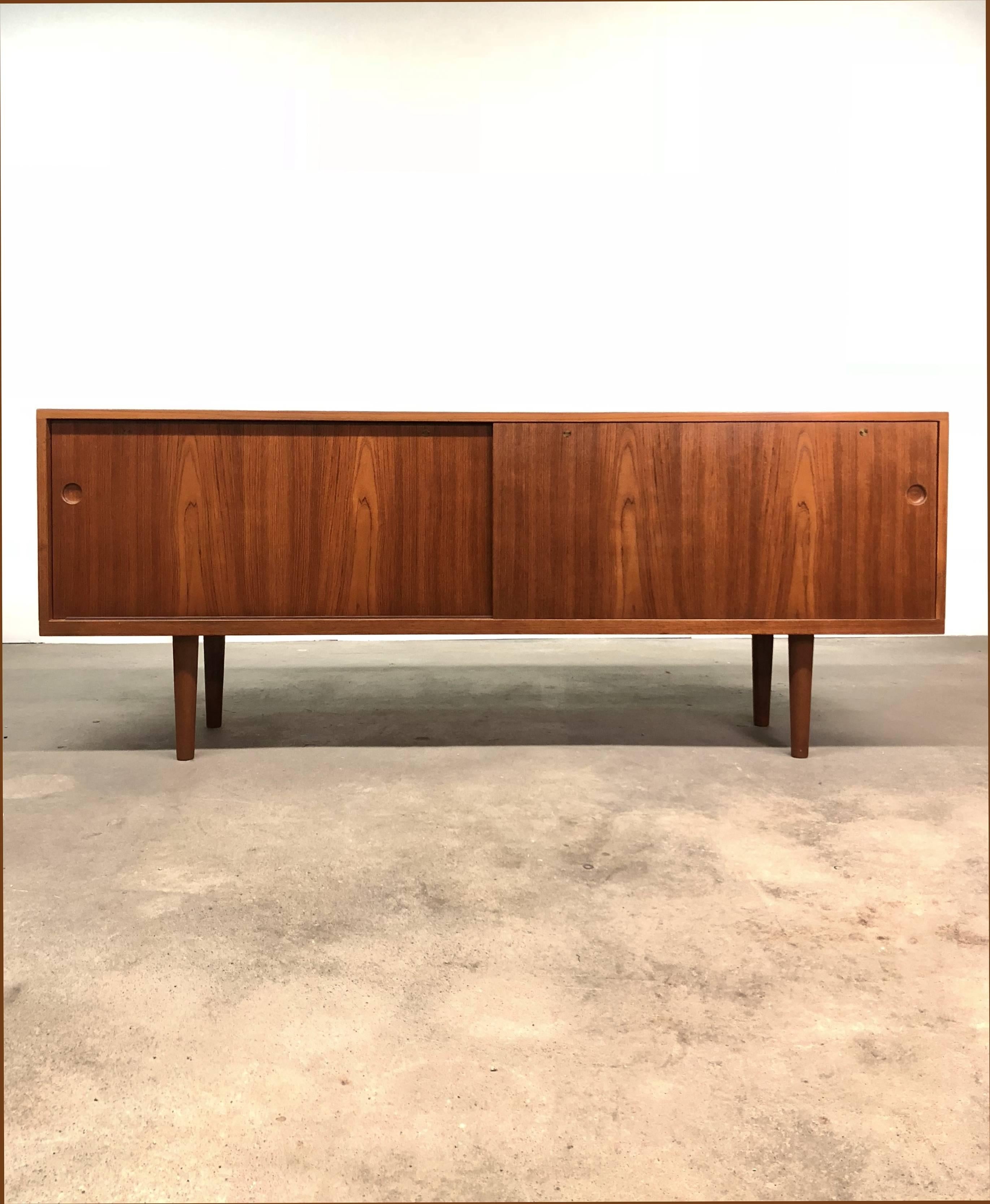 Credenza/sideboard model 26, in Teak, oak and brass, designed by Hans J. Wegner and produced in Denmark by Ry Møbler, circa 1966. Credenza features sliding doors, that open to reveal a series of storage spaces, adjustable shelves and drawers.