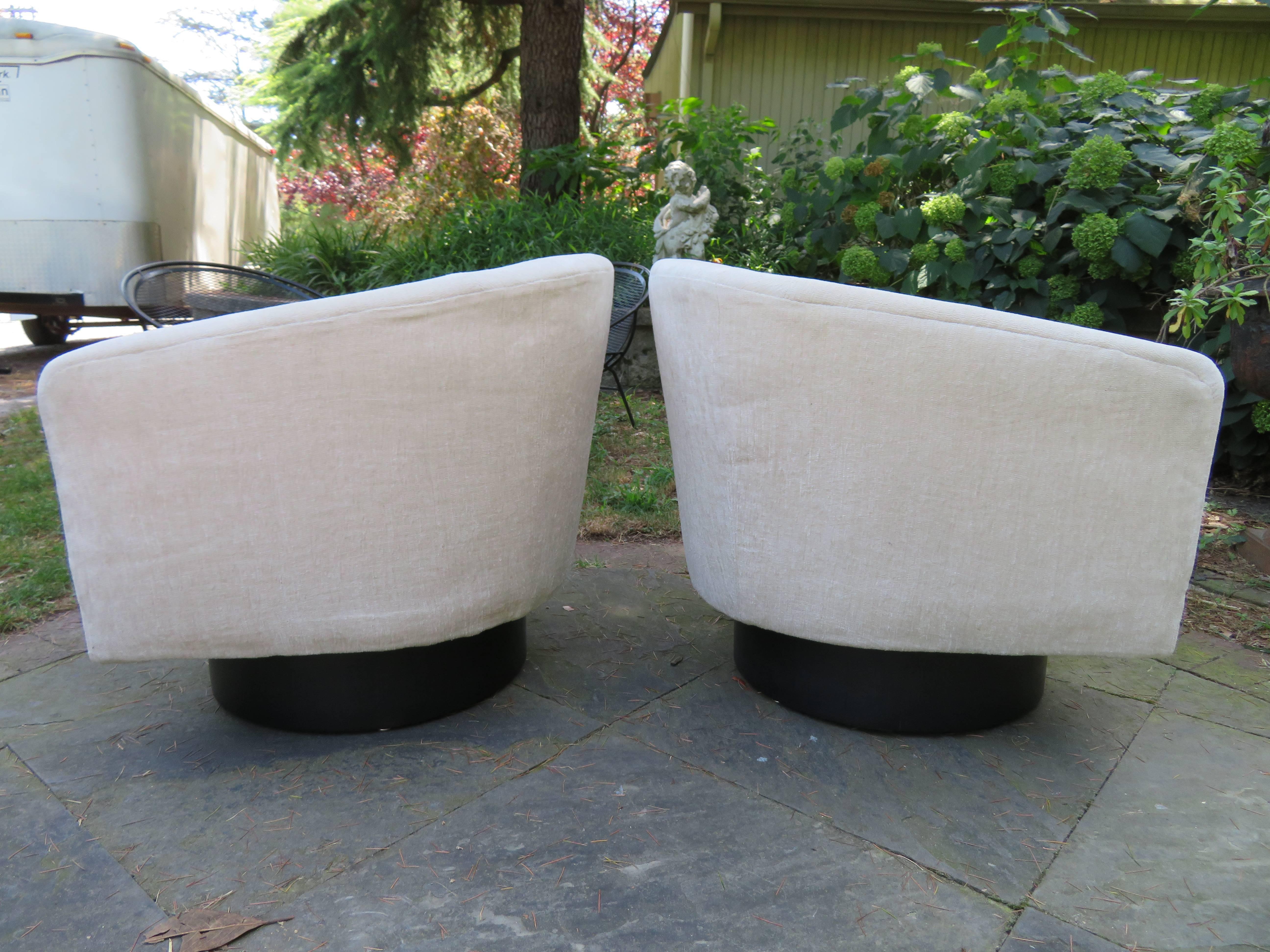 Fantastic pair of Milo Baughman tall swivel base barrel back lounge chairs. The unique tall swivel bases have an ebonized finish and look very nice. This pair retains their original fabric and will need new upholstery.