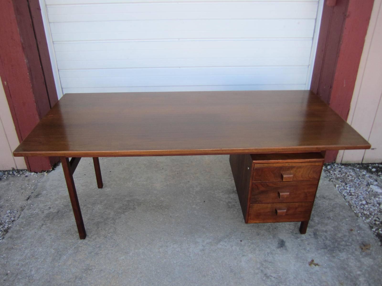 Handsome midcentury single-pedestal walnut desk made by Jens Risom. This desk features three drawers with a pencil drawer and a pull-out surface. This classic piece of modern Danish design will look great in any home or office.