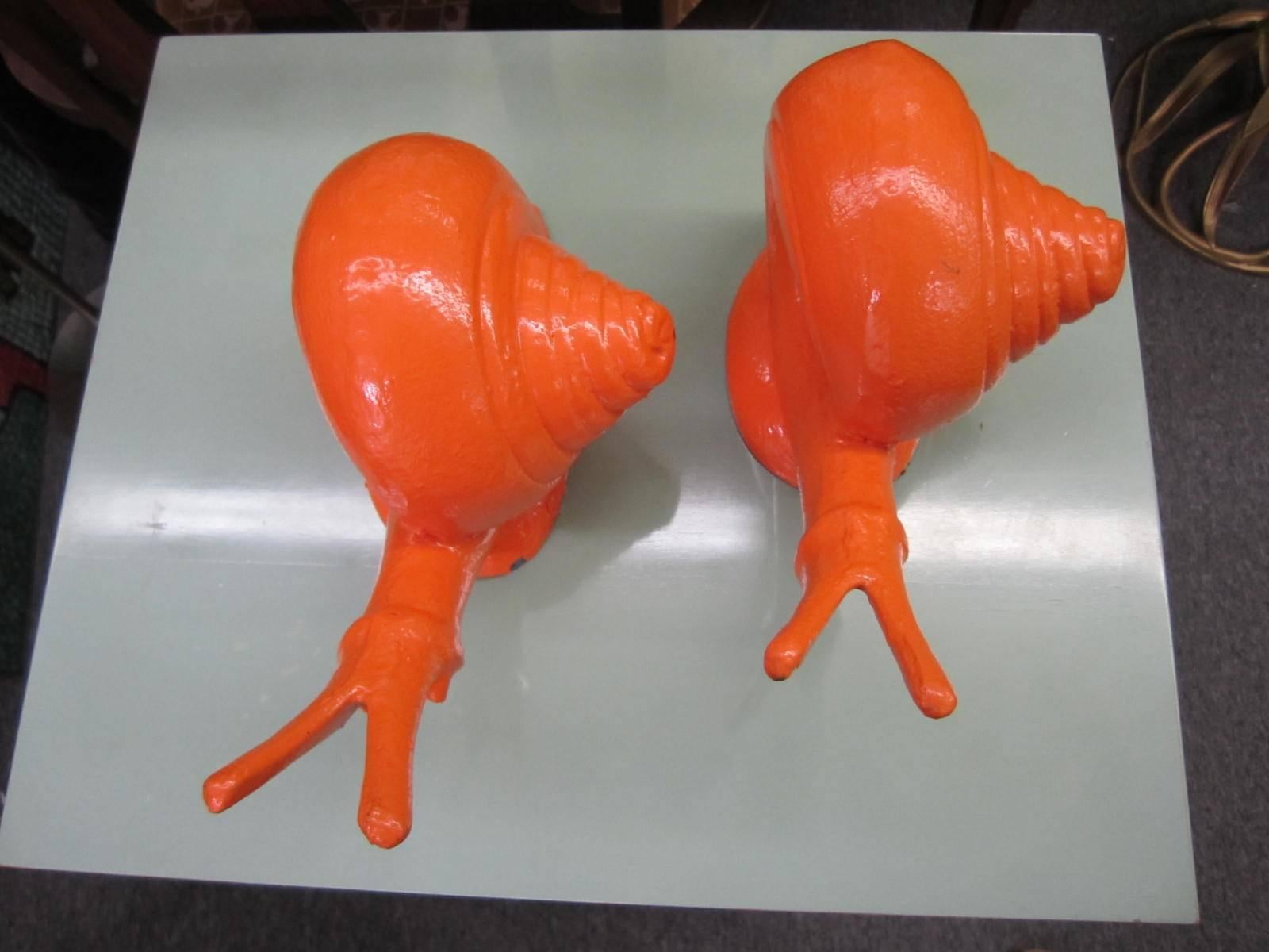 Whimsical pair of cast iron painted orange snail bookends. We love the large-scale and pop color of these fun holders of books.