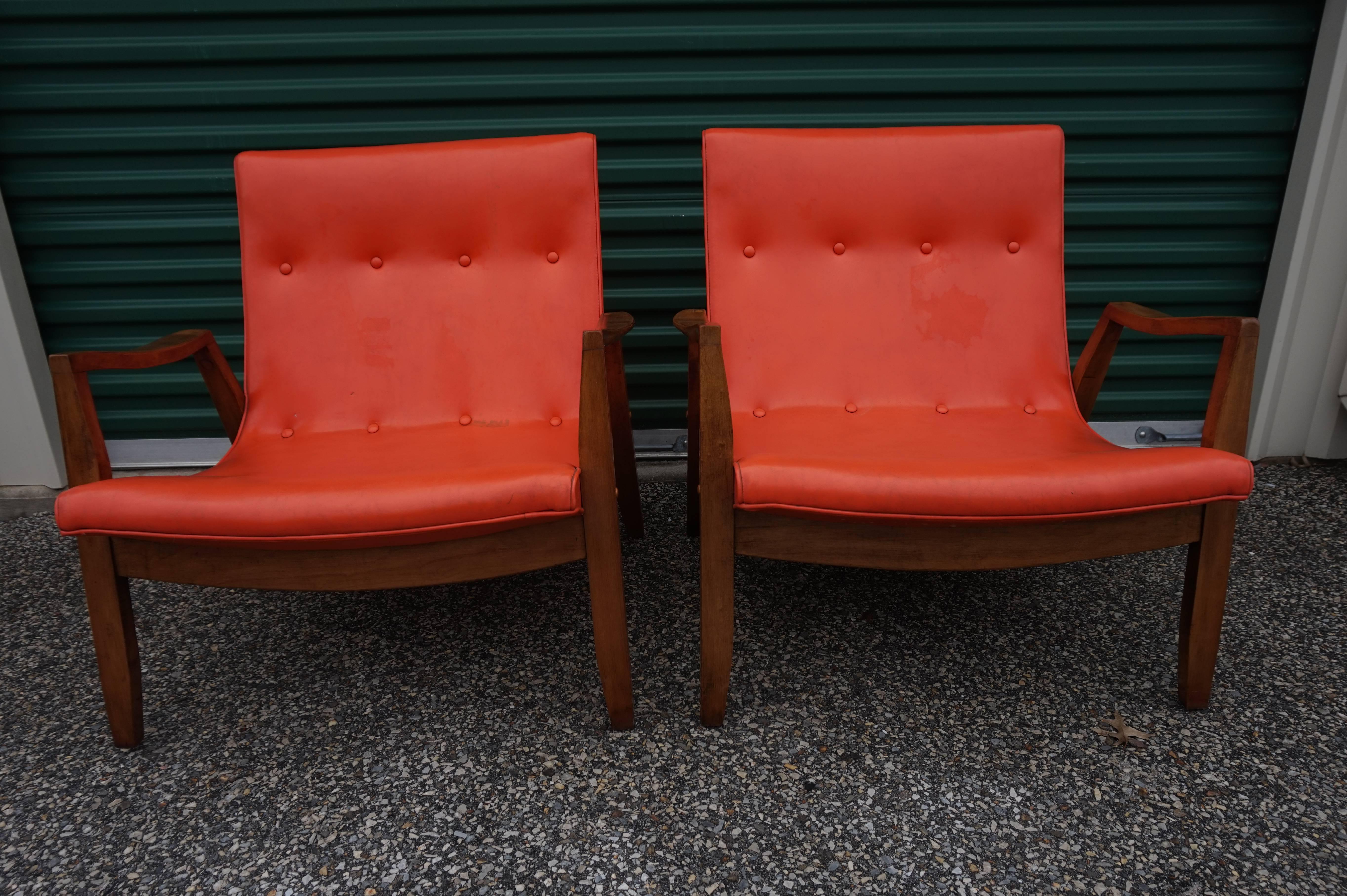 Early pair of Milo Baughman signed scoop lounge chairs with light walnut frames. Original orange vinyl shows wear-re-upholstery is recommended. James inc. tag on underside of one.