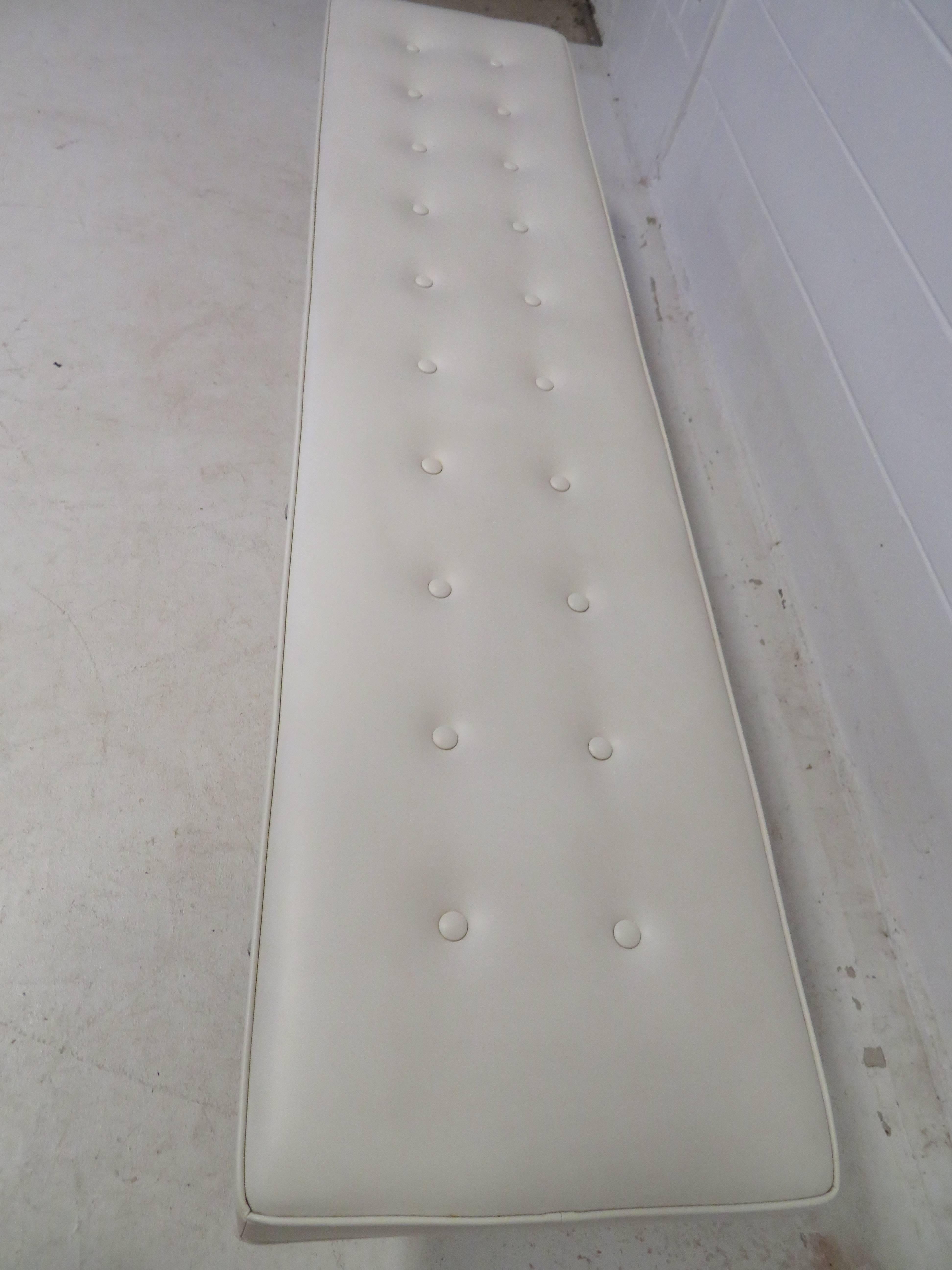 Magnificent Herman Miller style long faux white leather tufted bench with polished aluminum three-legged base.